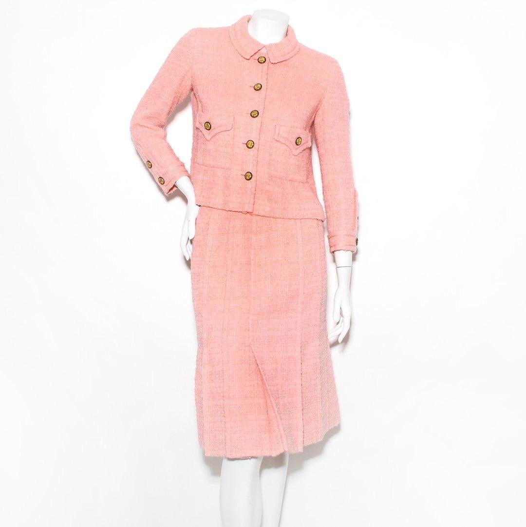 Product Details:
Pleated skirt suit by Chanel
Lifetime Chanel 
Circa 1960's 
Pink Boucle suit  
Two front pockets 
Button front and snap collar closure 
Gold tone/black hardware 
Button cuff faux closure 
Pleated skirt 
High waist 
Zip and hook and