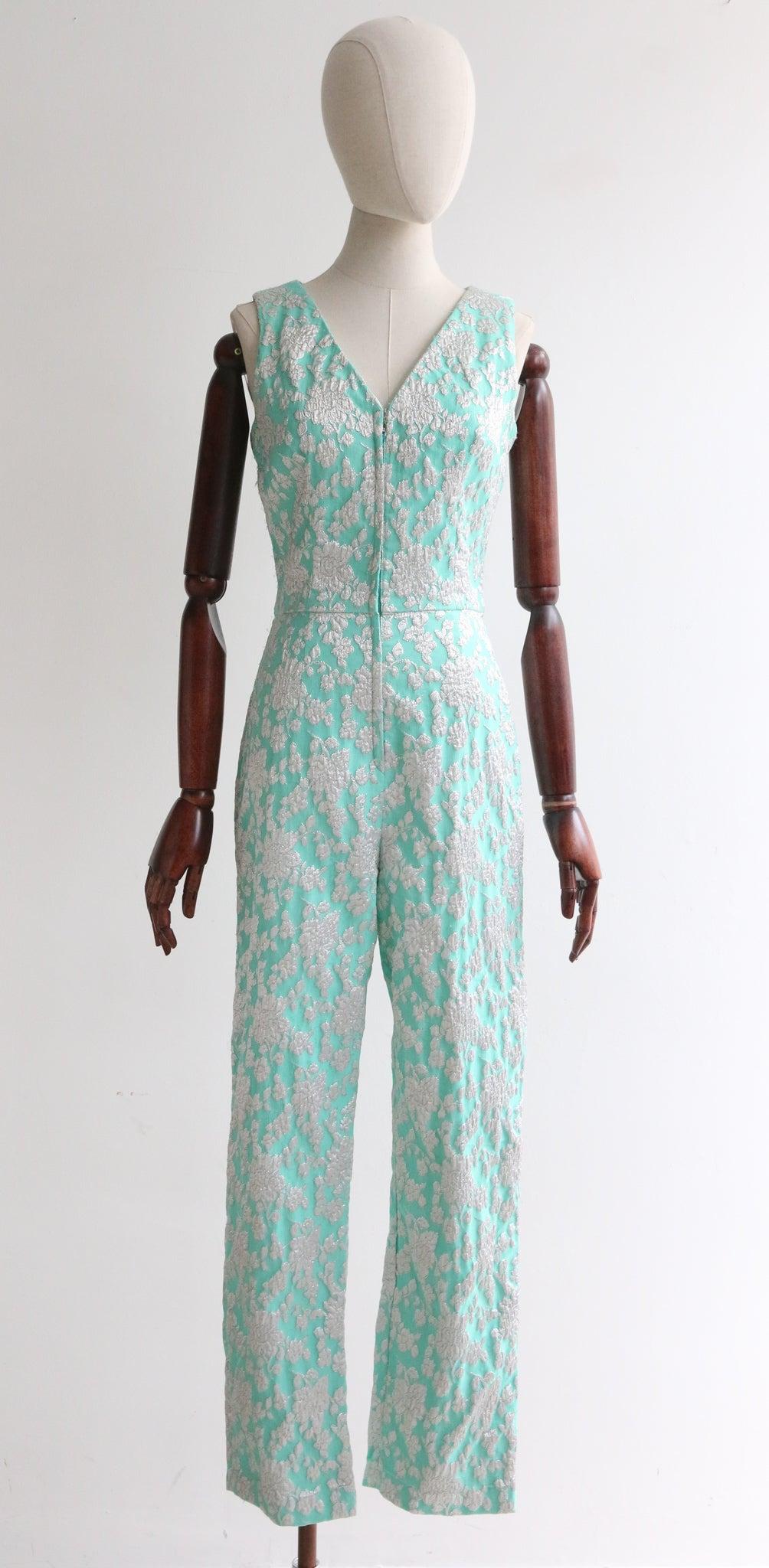 An iconic piece, this original 1960's jumpsuit and matching coat in an ice blue brocade with silver floral lurex accents, is the perfect statement piece for your vintage wardrobe. 

The V shaped neckline is framed by wide shoulder straps and a