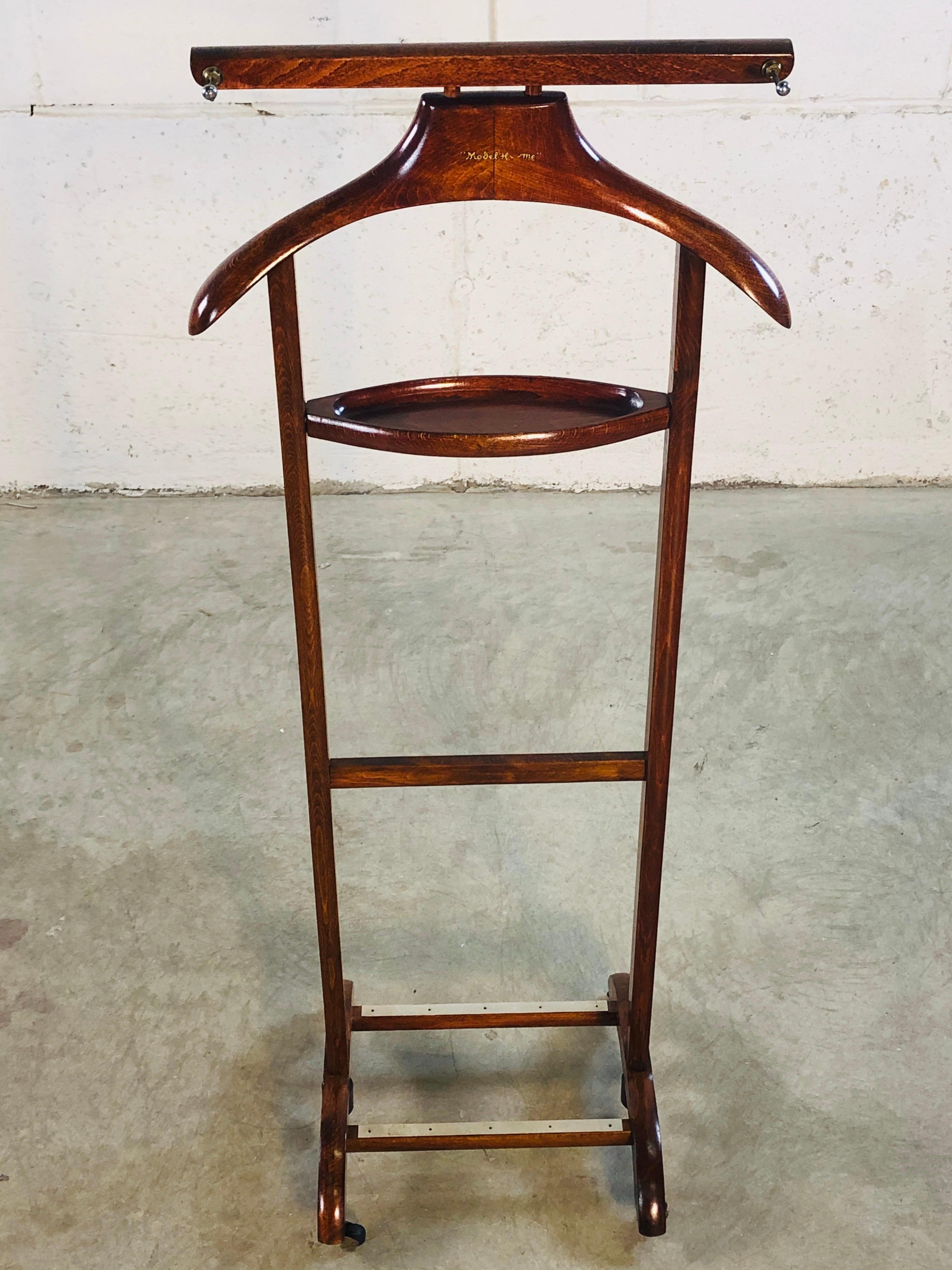 Vintage 1960s men’s bedroom valet stand on wheels. The valet is a dark maple wood with two tie hooks and a shelf for change and cufflinks. No marks.