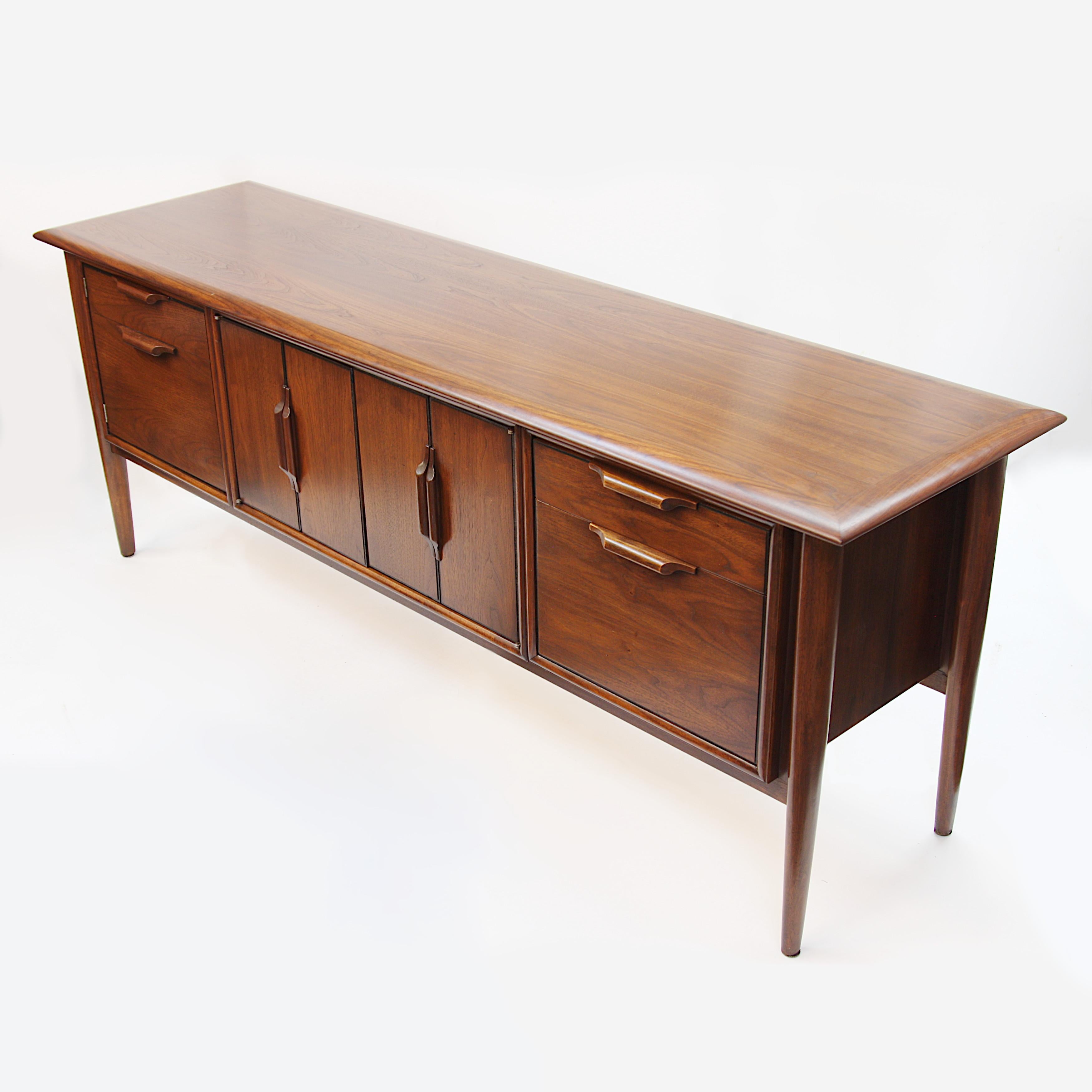 Stunning Mid-Century Modern credenza made in Highpoint, North Carolina by the Alma Desk Company. Part of Alma’s “Castilian” line. Credenza features center accordion doors, file drawer, pull-out shelf, gorgeous, floating legs and thick, rounded-edge