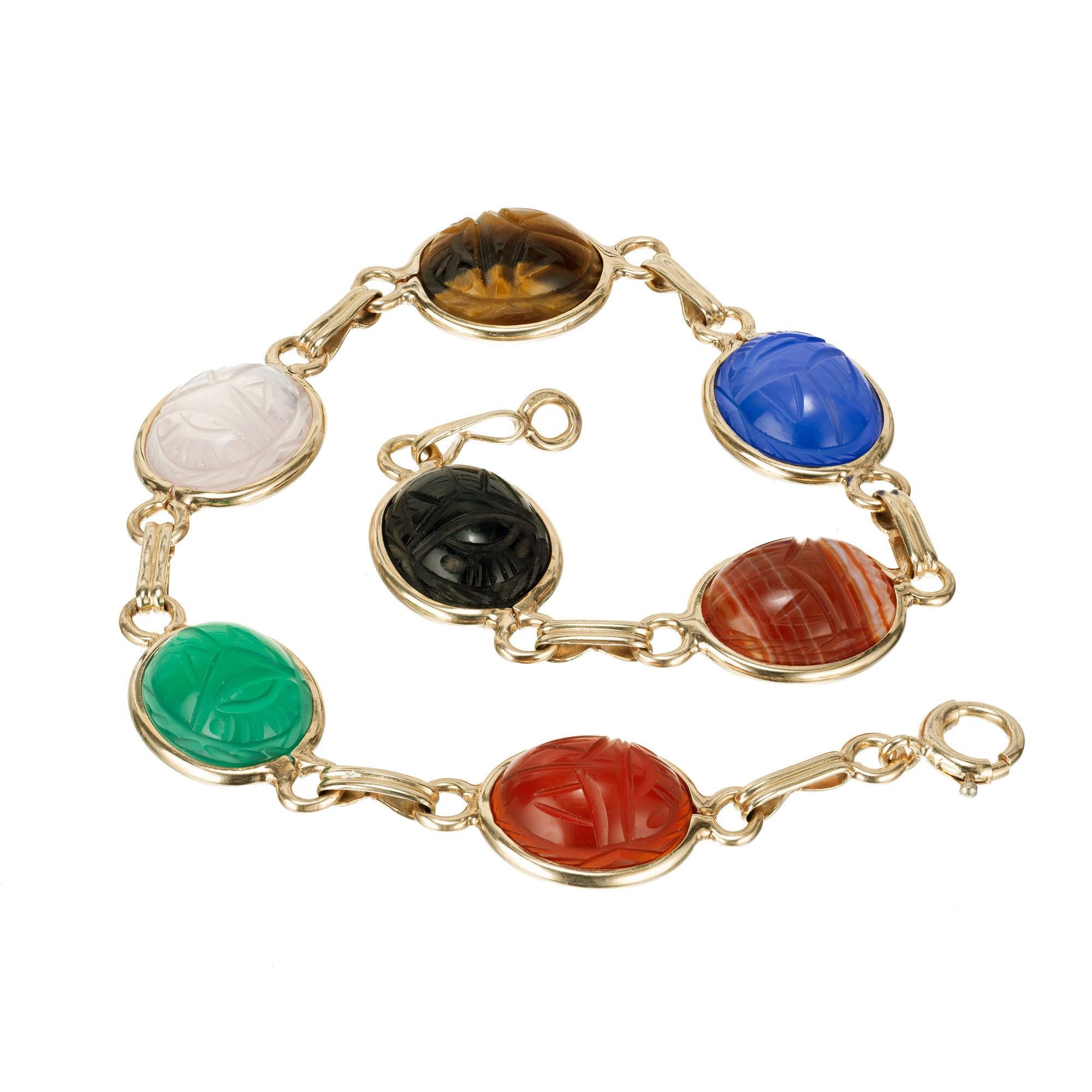  Seven stone bezel set, 1960’s classic multi-color Quartz, carnelian, chrysophase, turquoise, blue chalcedony, agate and onyx  scarab link bracelet carved front and back. 

1 oval Carnelian 10.84 x 8.99 x 5.40mm 
1 oval Chrysophase 
1 oval rose