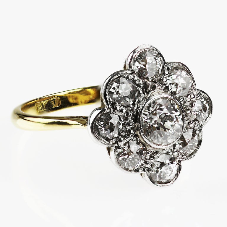 A show-stopping vintage 18ct gold diamond cluster ring. 
The central diamond weighing 0.40ct is framed by a glittering arrangement of nine Old-European cut diamonds (totalling 0.75ct), which form a beautiful cluster resembling a flower. The diamonds