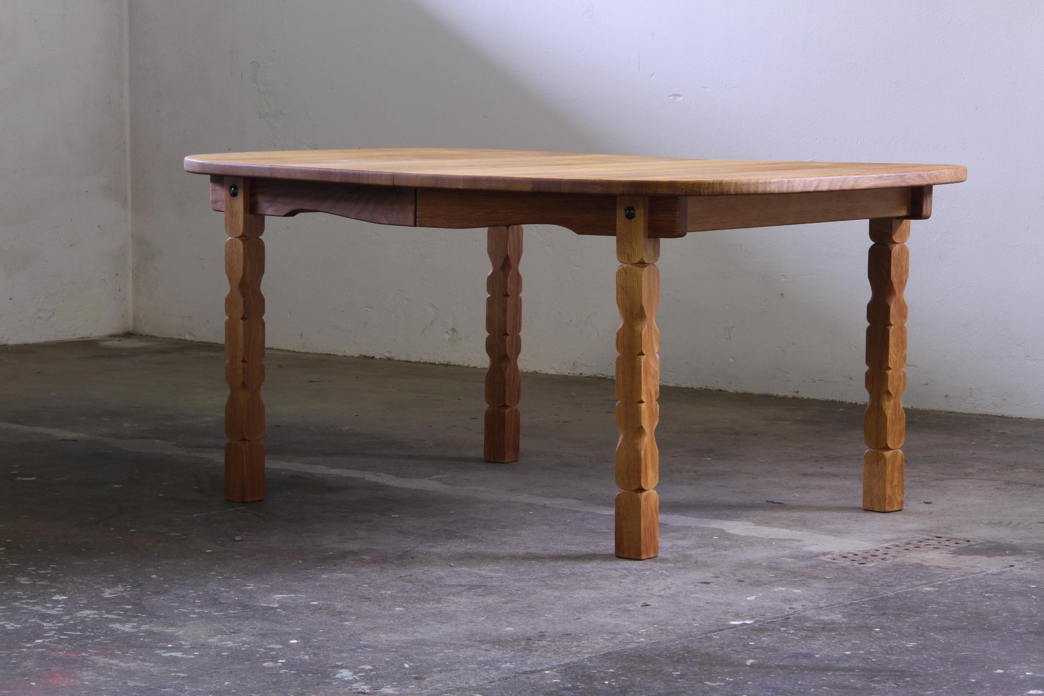 This vintage oak table captures the essence of Henning Kjærnulf's design philosophy, blending a bold brutalist aesthetic with refined craftsmanship. The intricate leg carvings harmonize beautifully with the table's rounded shape, creating a piece