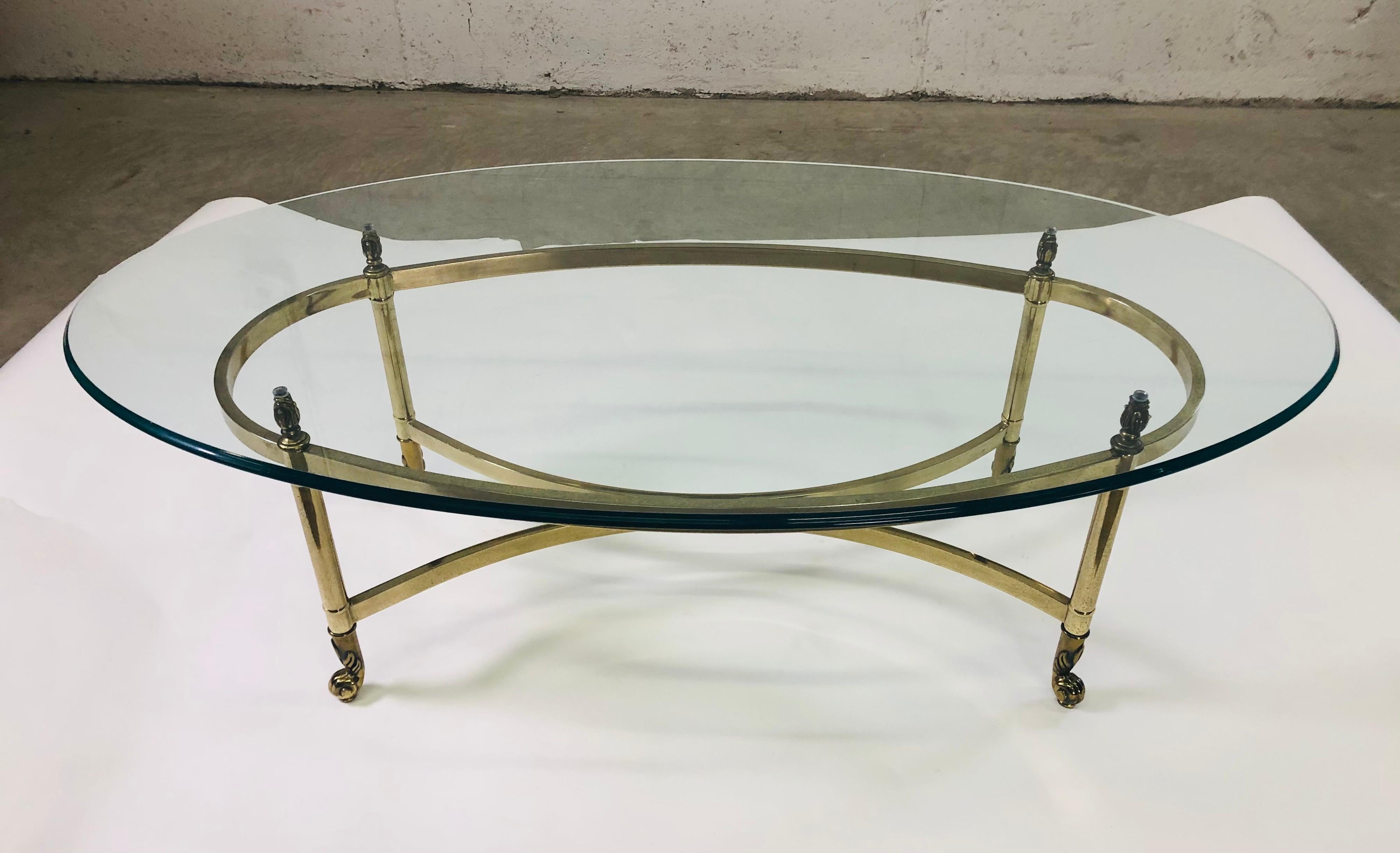 Vintage 1960s oval glass top with brass base coffee table by Labarge. The table has scroll brass feet. No marks.