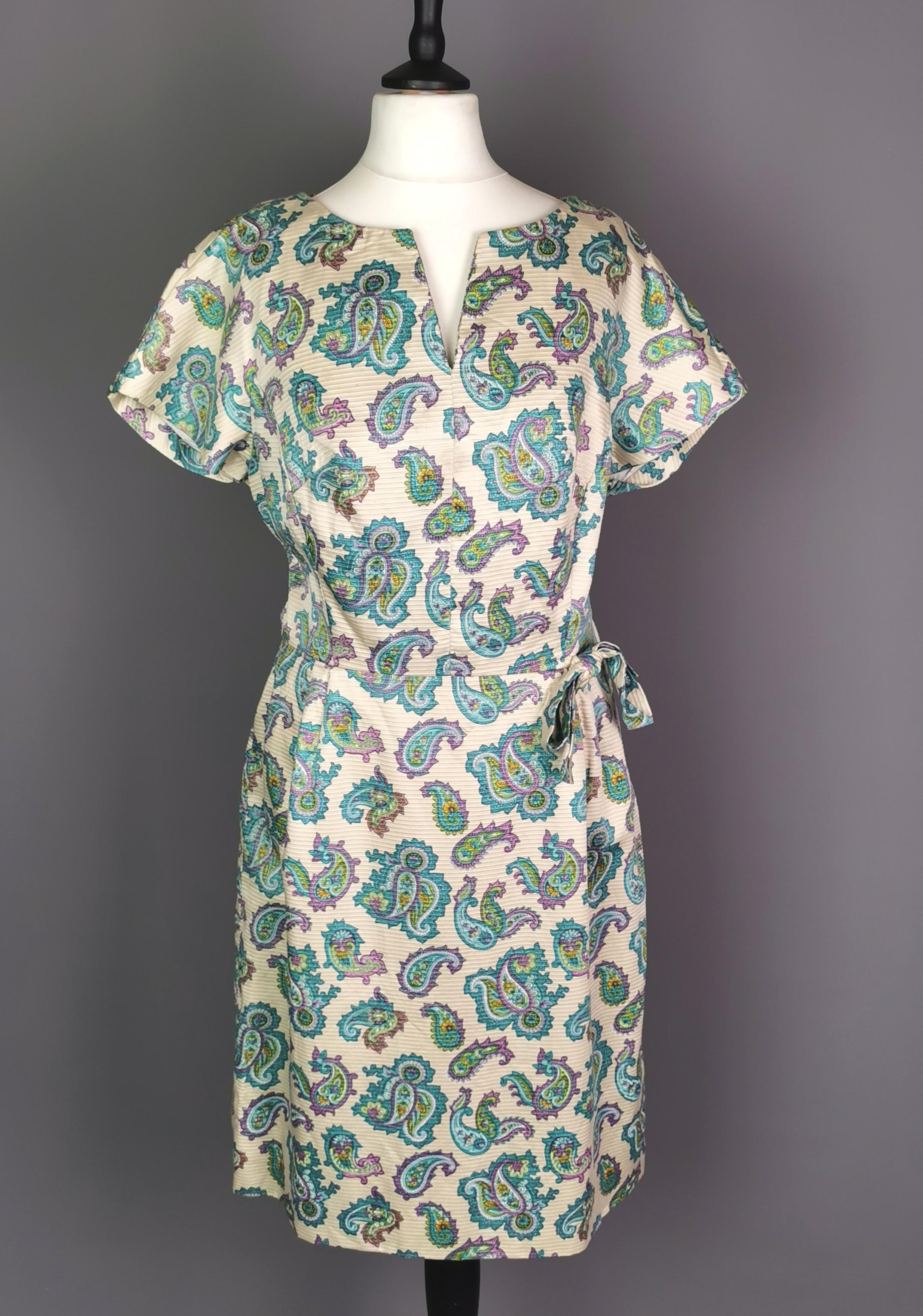 A fantastic vintage late c1960s paisley print mini dress.

It is made from a synthetic rayon satin blend, nipped in slightly at the waist with a fairly straight cut skirt in a vibrant paisley pattern on a dark cream ground, very colourful.

It has a