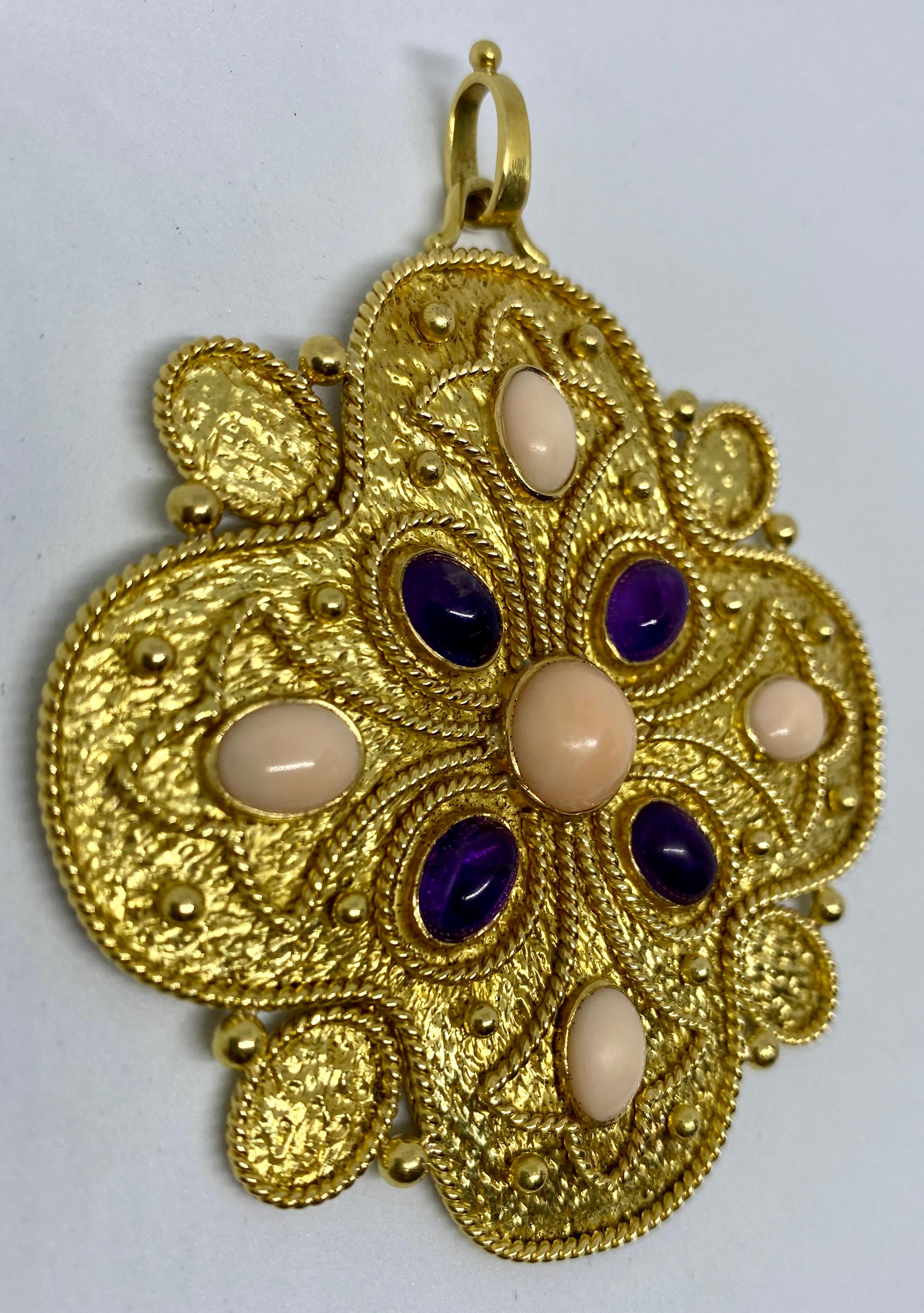 A breathtaking pendant in hammered 18K yellow gold featuring amethyst and angel skin coral cabochons and rope details.

Pieces from this era by Vourakis, one of the 