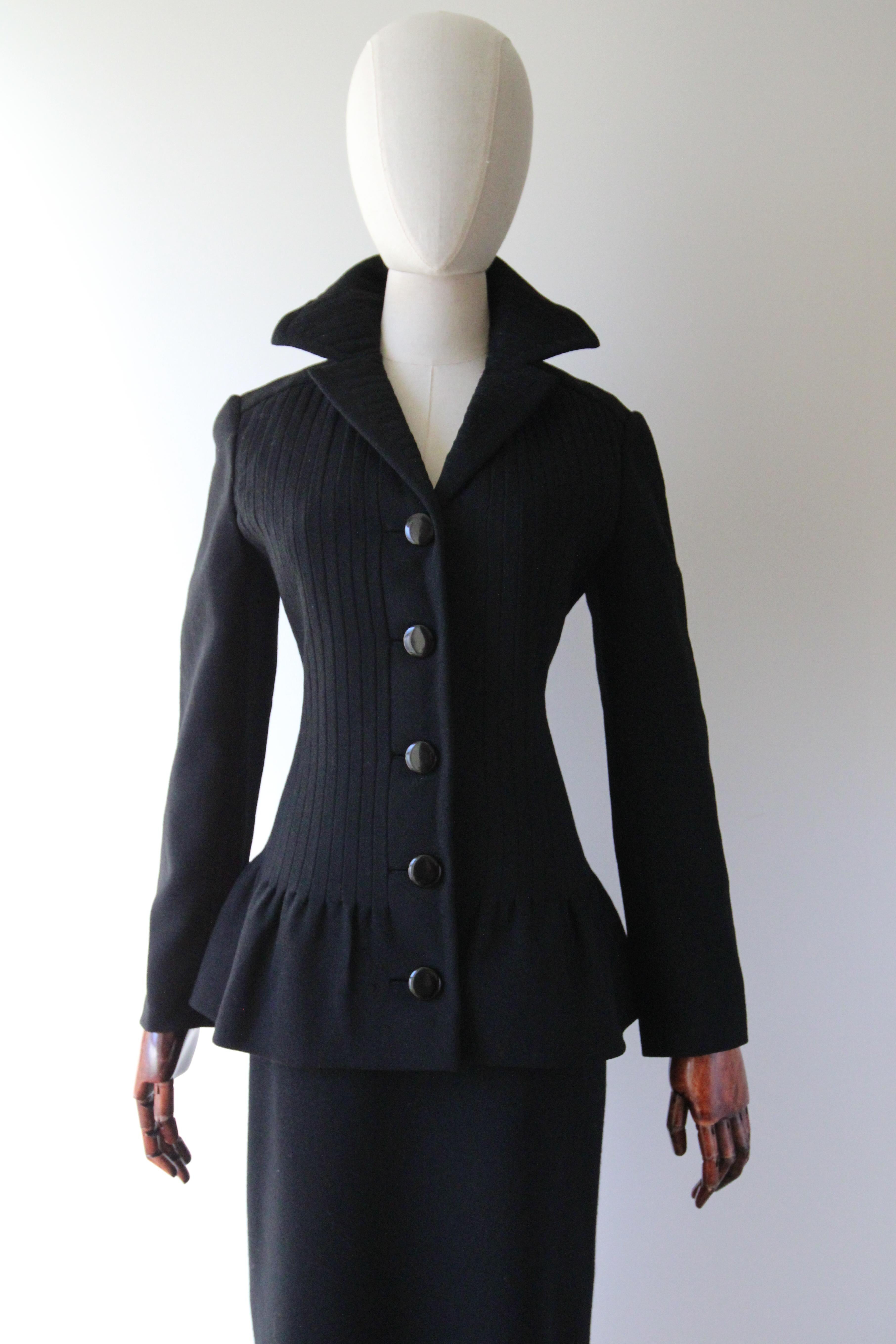 This beautifully tailored 1960's Pierre Cardin black wool skirt suit, rendered in an iconic 1960's silhouette, is the perfect addition to your vintage collection. 

The V shaped neckline of the jacket is framed by a notched collar which boasts