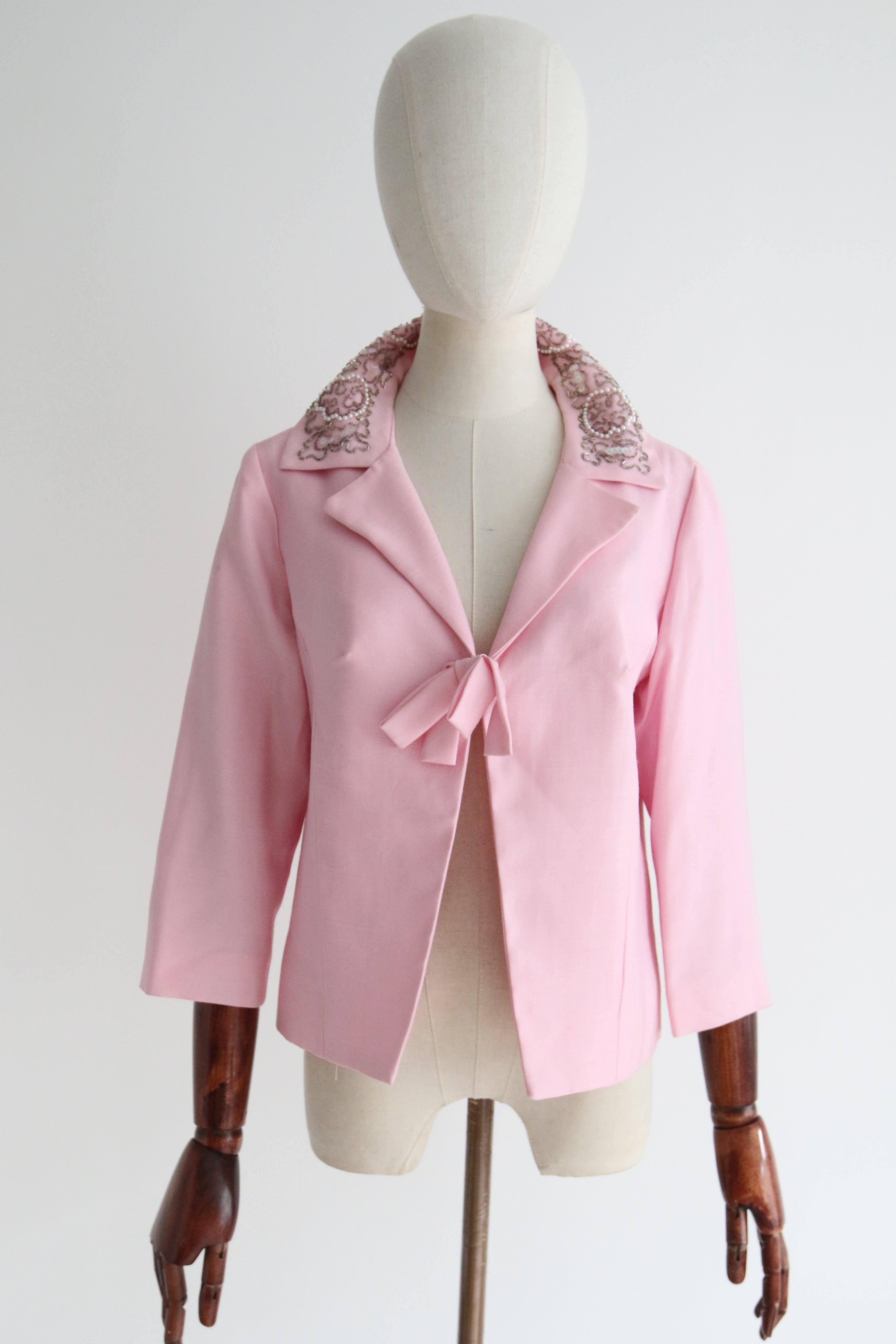 Rendered in the most vibrant shade of ballet pink and accented by detailed beadwork along the collar, this original 1960's silk jacket is the perfect staple to your vintage collection.

The V shaped neckline is framed by a pointed and notched collar