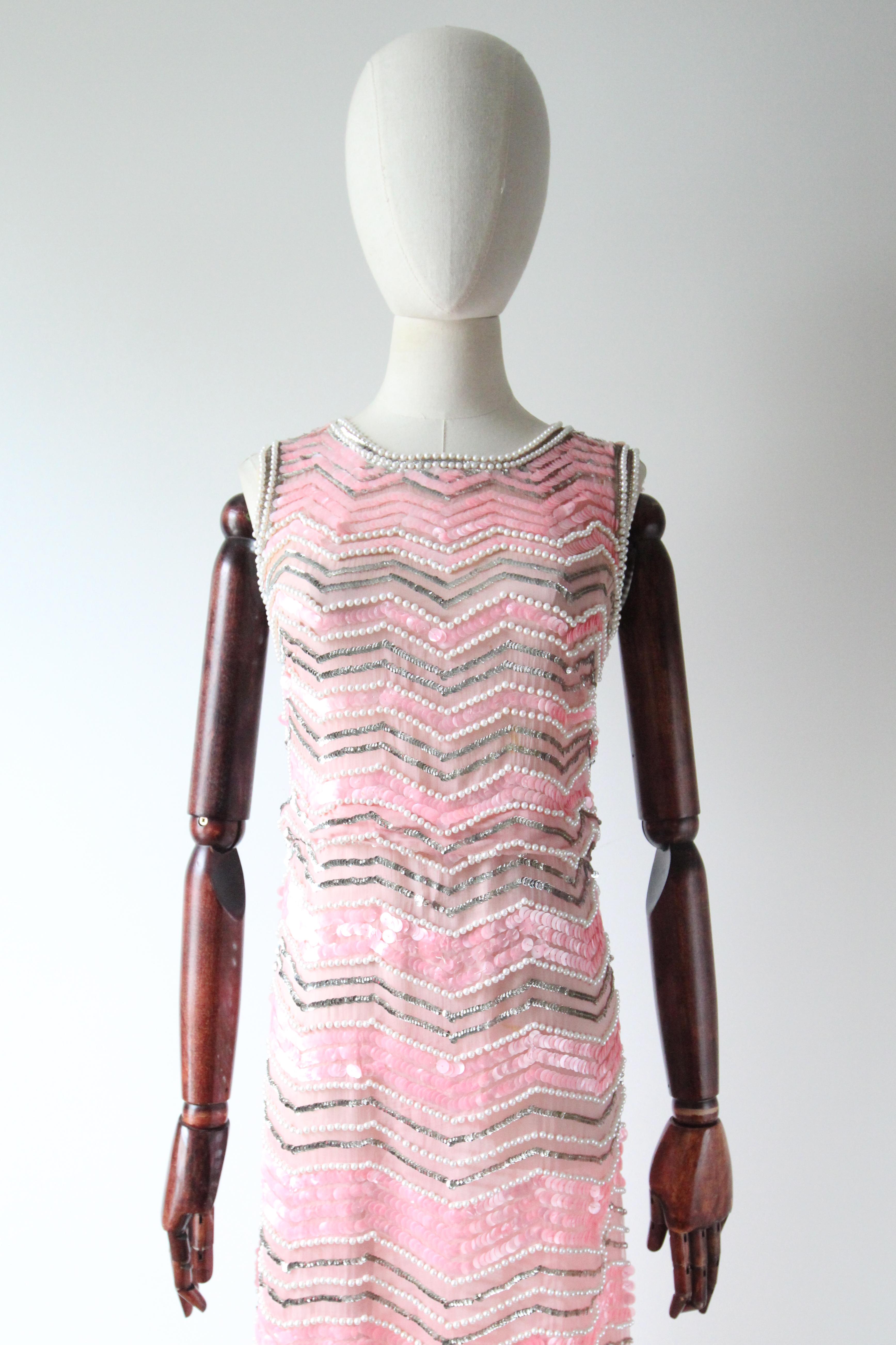 This truly spectacular 1960's silk organza dress, embellished in a striped pattern of pearlescent beads, silver sequins and large pink pearlescent sequins, is a masterpiece to behold and the perfect piece for your cocktail wardrobe.

The rounded