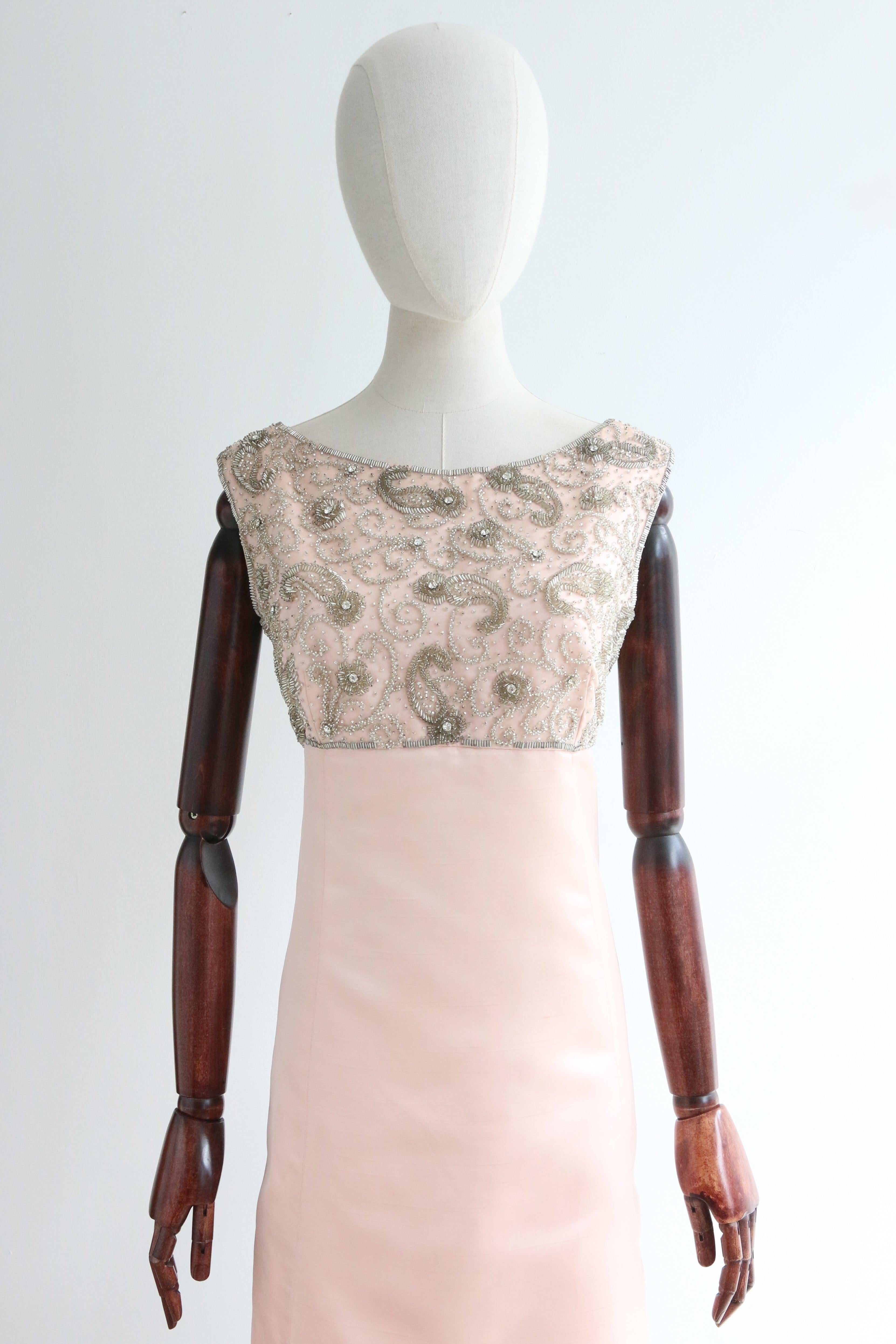 Realizzato nella più morbida tonalità di raso rosa e decorato con perle di vetro argentate, perline argentate e grandi strass argentati incastonati, in un design paisley, questo originale abito da cocktail Malcolm Starr degli anni '60 è il pezzo