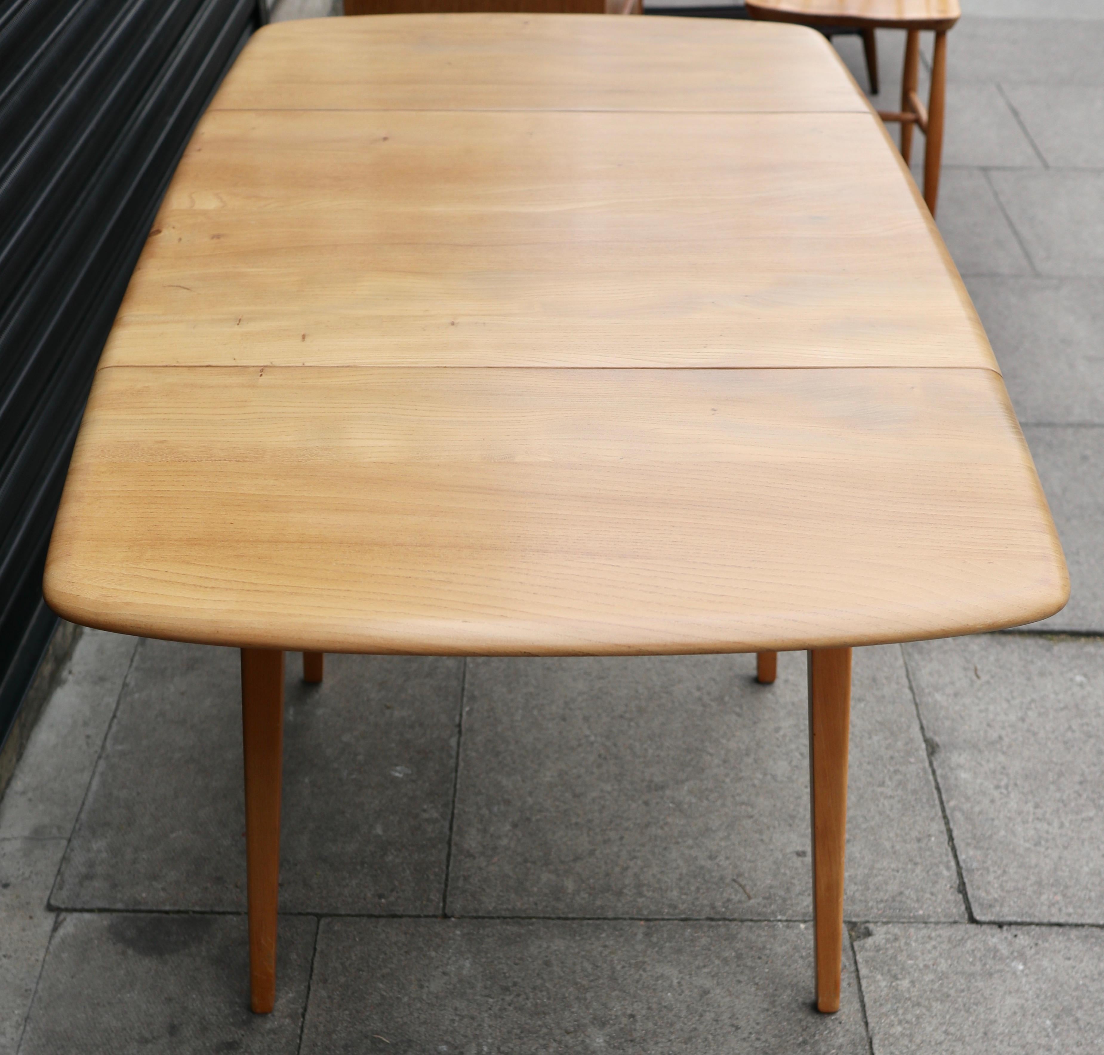 A vintage 1960s drop leaf ercol rectangular dining table.  This table has a solid Elmwood top and a four legged solid Beech base. It has two drop leaves and is very good vintage condition, having been completely refurbished and refinished.