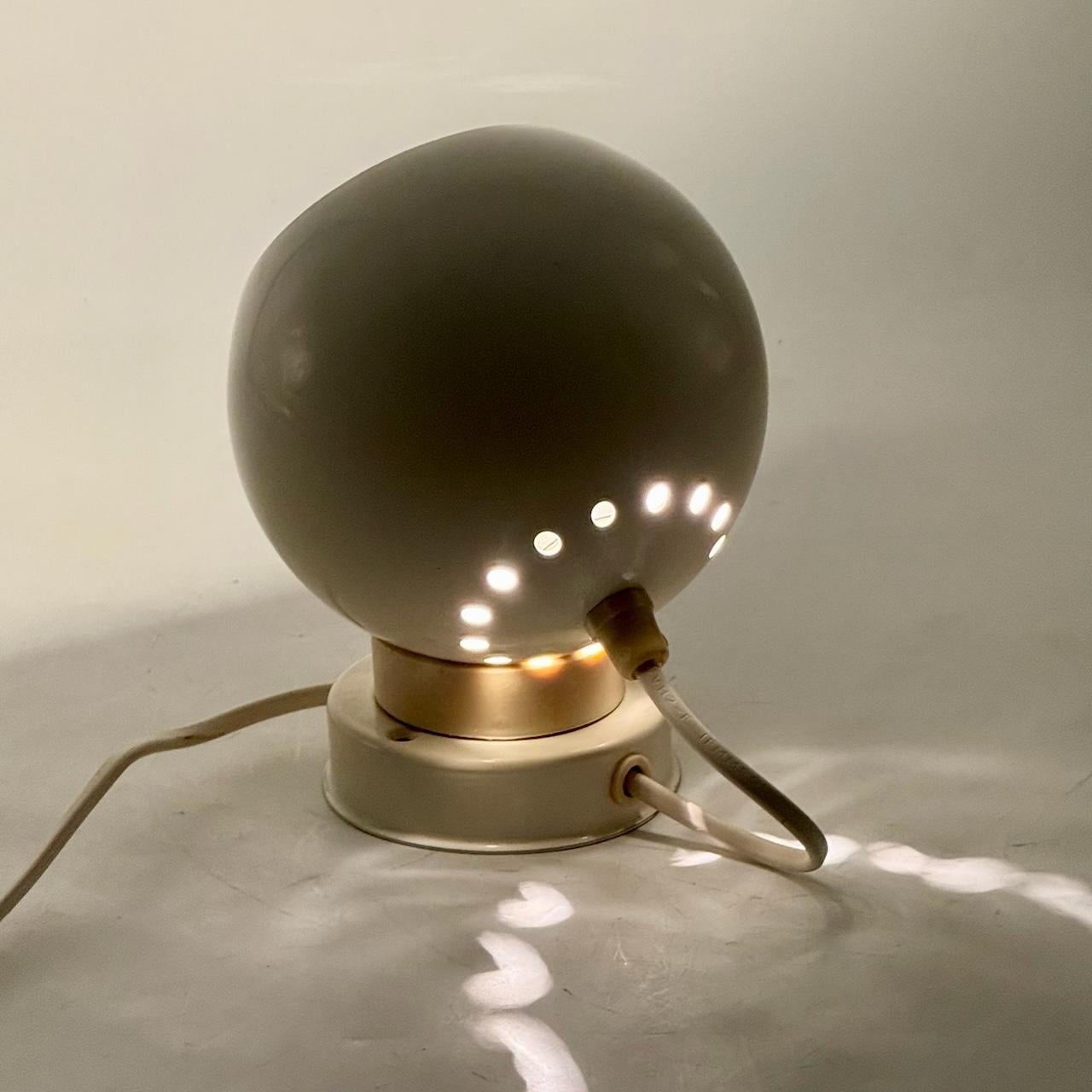 Icona senza tempo del design italiano degli anni '60, questa lampada Eyeball di Goffredo Reggiani può essere utilizzata come lampada da parete o da tavolo e offre un'illuminazione flessibile grazie al paralume sferico regolabile. Realizzata in