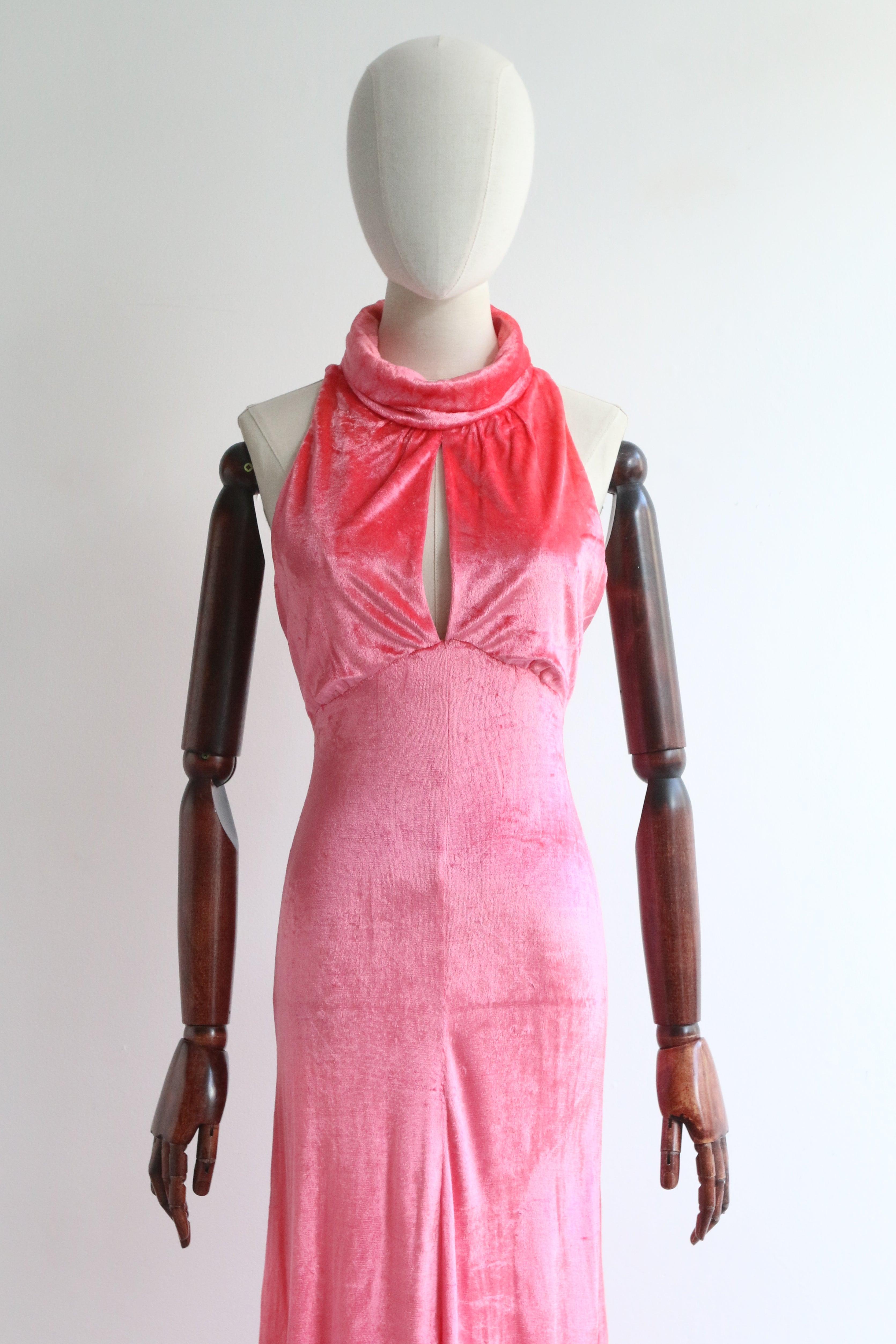 Cette vibrante robe de soirée des années 1960,  dans une nuance de velours rose des plus accrocheuses, est la pièce de choix pour votre garde-robe de soirée.

L'encolure haute et arrondie est rehaussée d'un col rabattu en forme de vache qui se