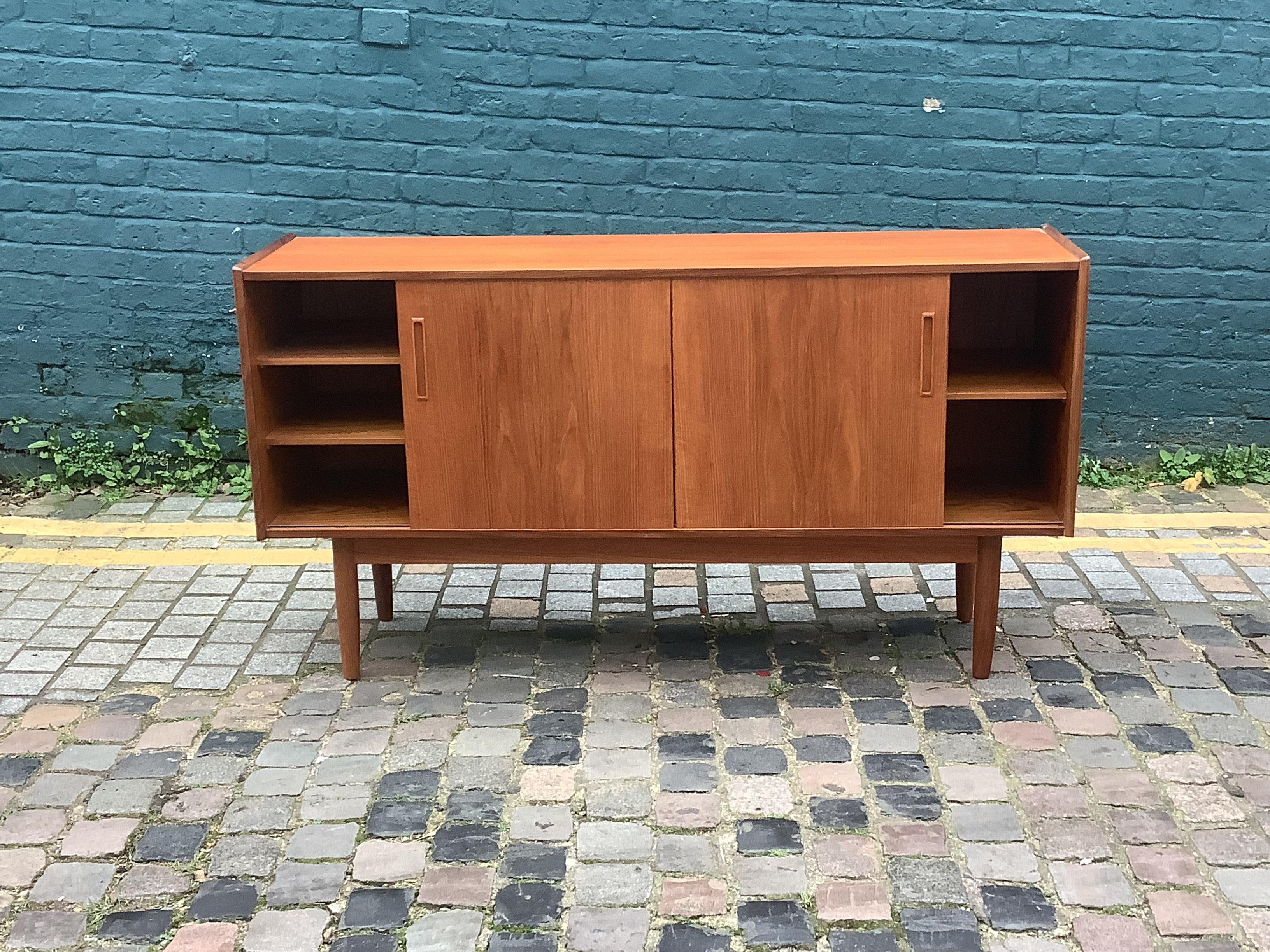 Stylist teak sideboard with useful storage shelves with sliding doors
Sitting on lovely tapered wooden legs Cc1960 Danish 