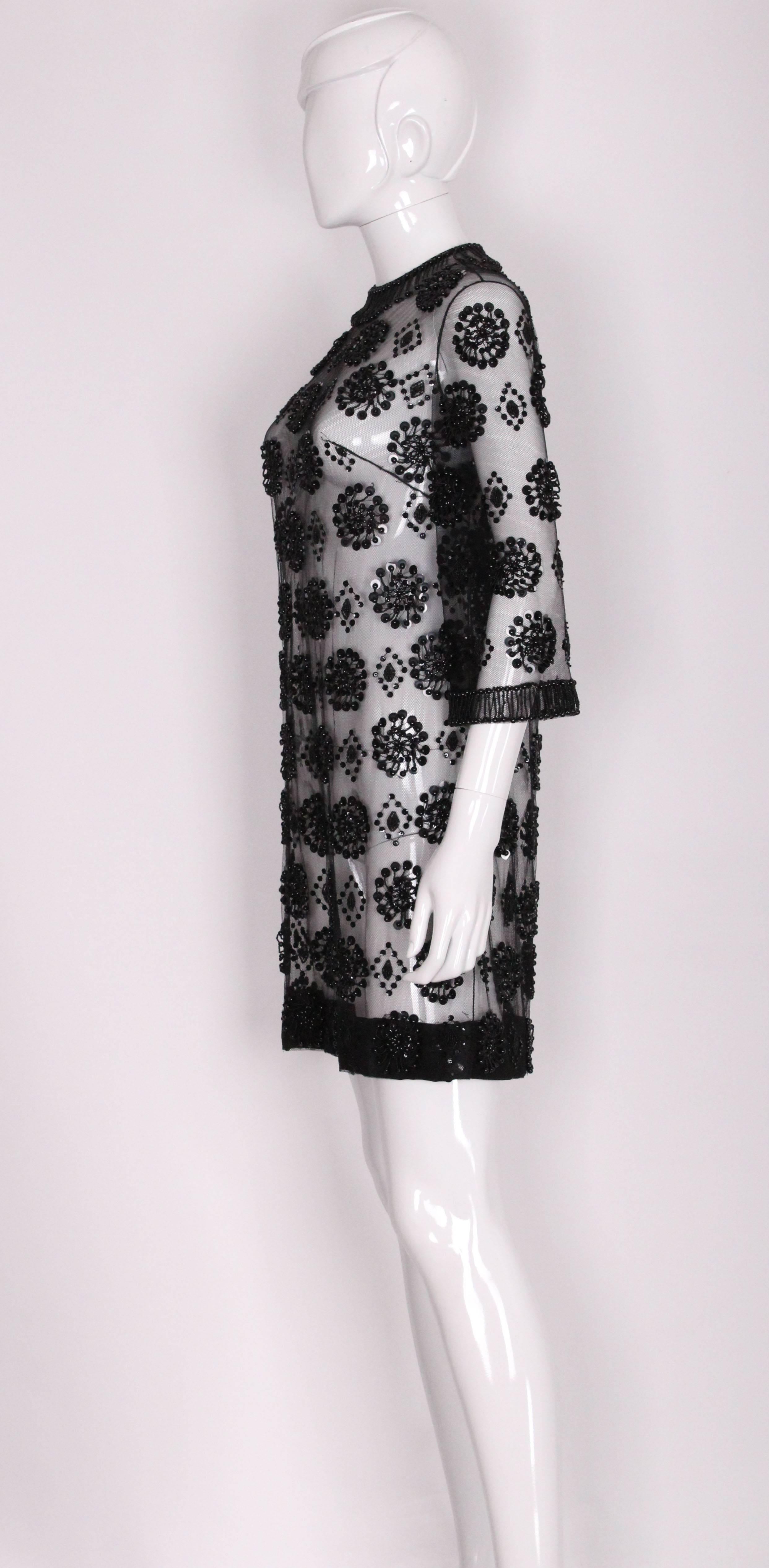 A super chic 1960s black beaded net cocktail dress in wonderful condition. The dress is made of net and the bead work is stunning, in a floral pattern on the body of the dress, front and back. There is some long bead detail around the neck and the