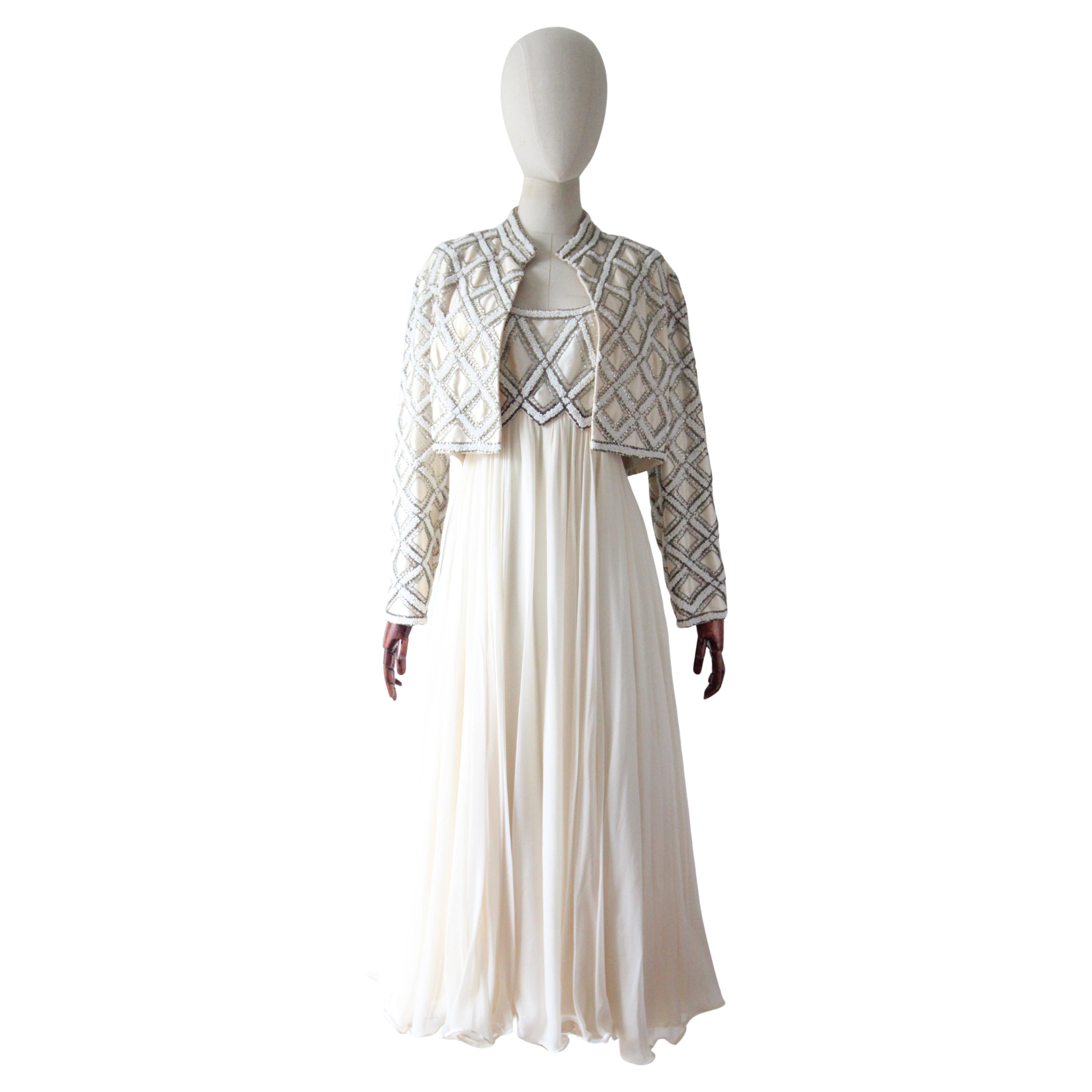 Dieses zeitlose Ensemble aus Kleid und Jacke aus Rohseide und Seidenchiffon aus den 1960er Jahren in einer ikonischen Silhouette, verziert mit auffälligen Glasperlen in Perlweiß und Silber mit schillernden Paillettenakzenten in einem
