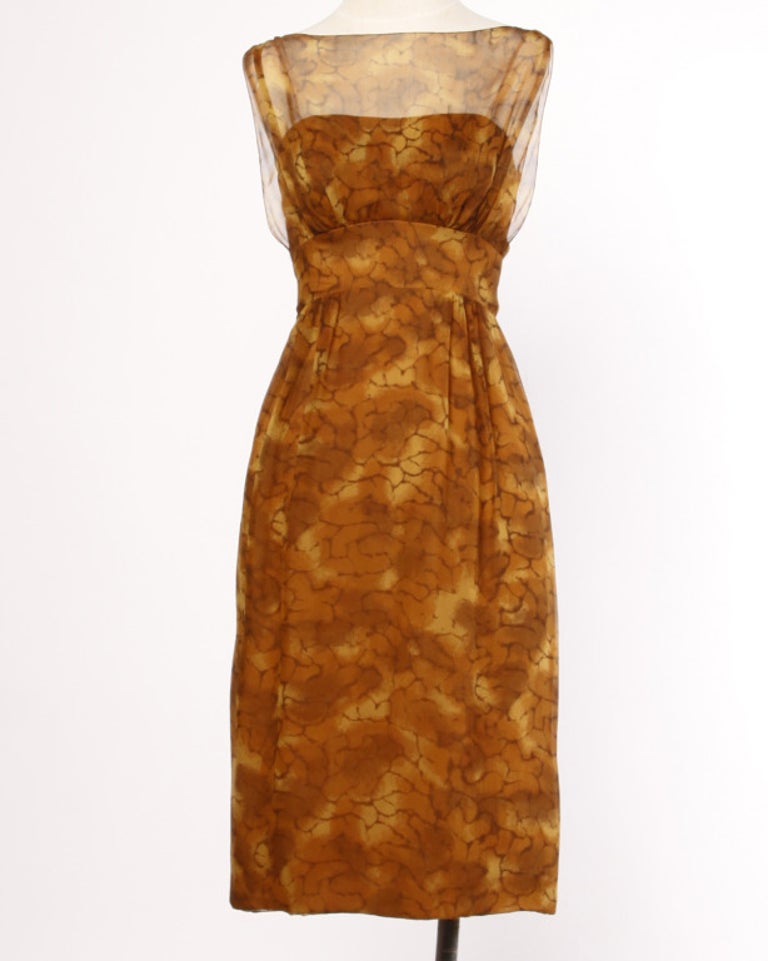 Luxurious paper thin printed silk chiffon in shades of umber, rust and mustard. We love the wiggle shape on this 1960's cocktail dress and the iconic sack-back that cascades down the back of the dress! The dress features an empire waist with an