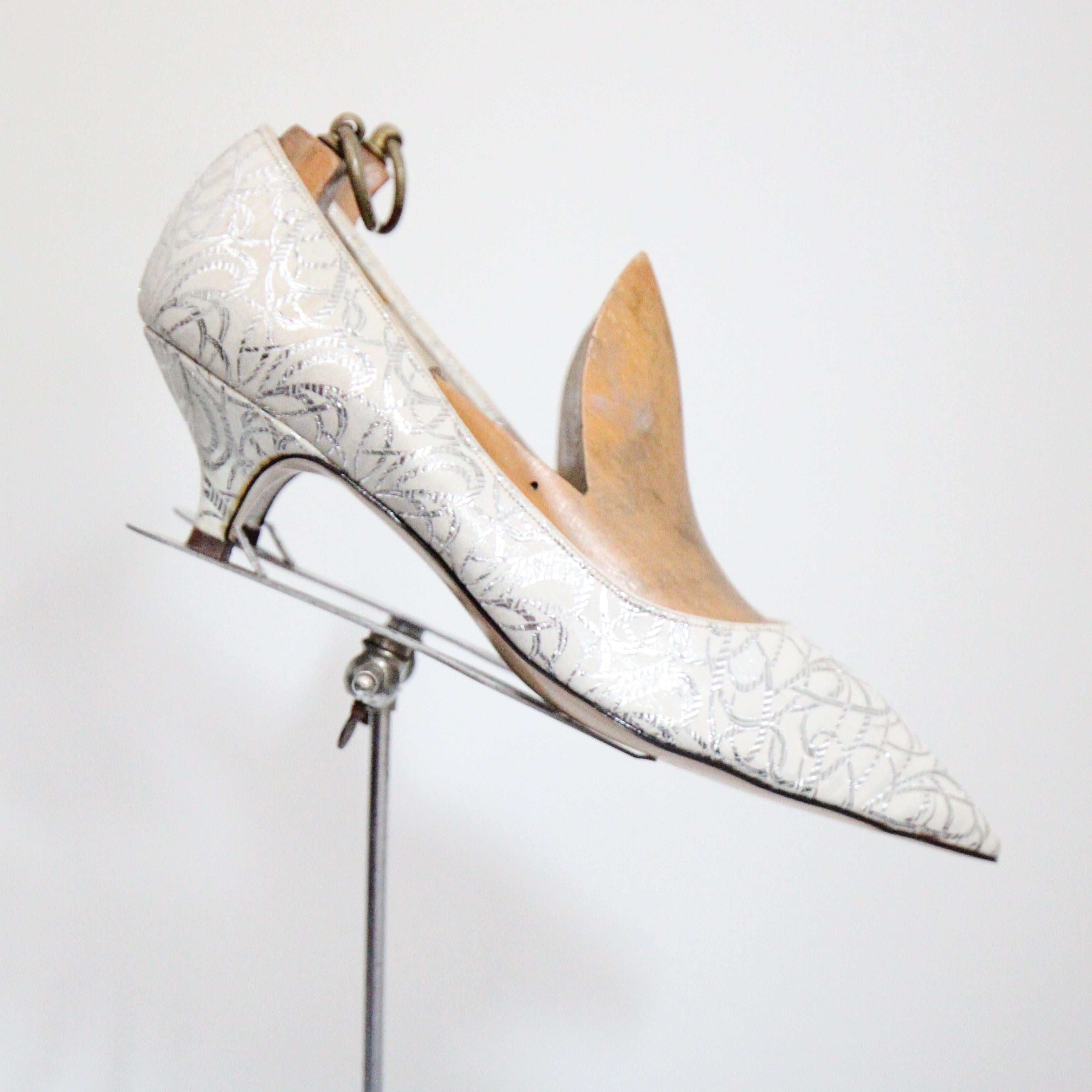 The most versatile little pair of 1960's heels you could ever hope to set eyes upon.  

The delicate shoe, with a sparkling silver and white lurex brocade intertwining design    encloses the front of the foot in a pointed toe.  The collar of the