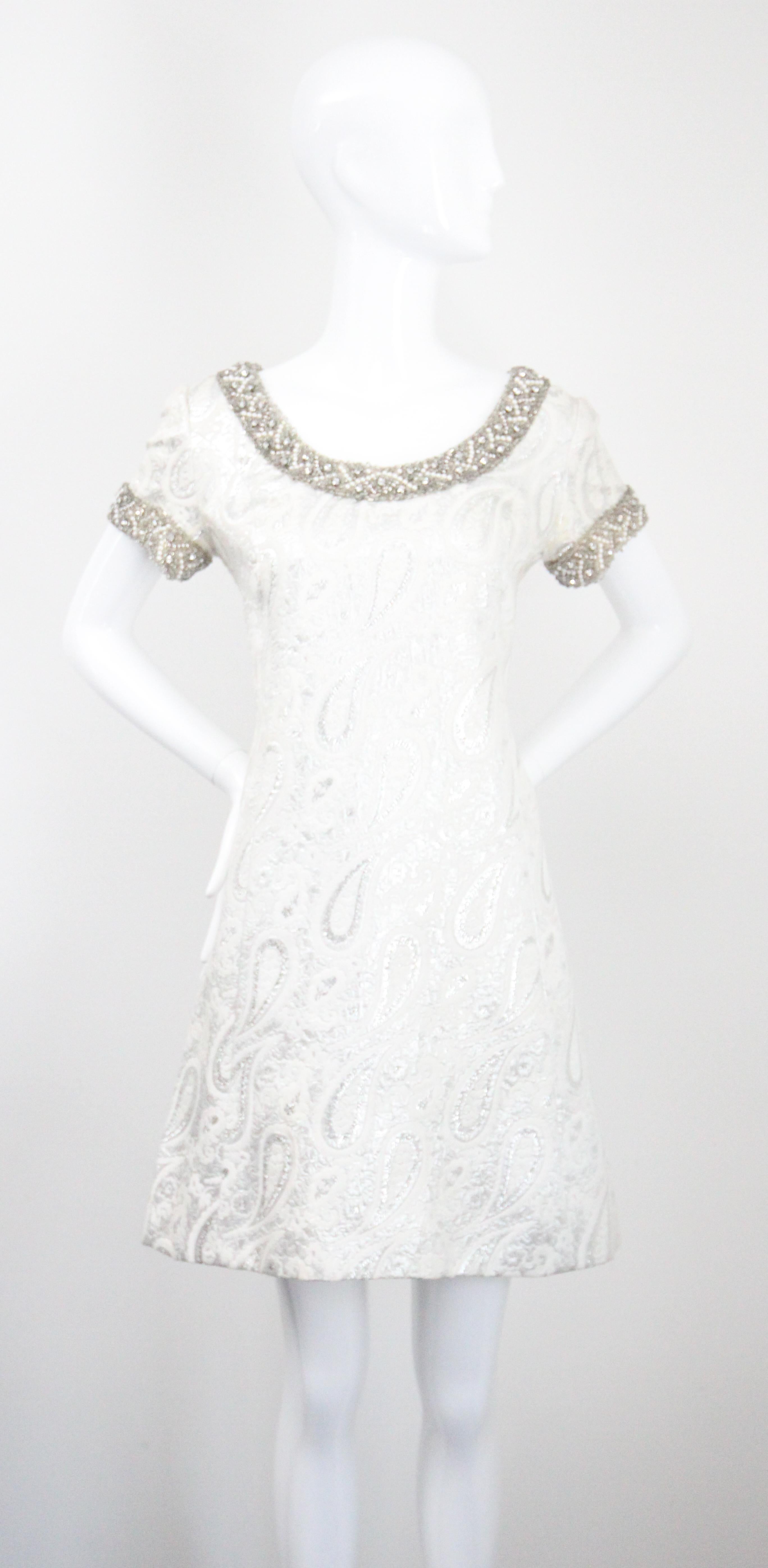 This truly breathtaking 1960's silver lurex brocade dress and matching coat ensemble, embellished with borders of silver glass beadwork, silver claw set rhinestones, pearls and silver plastic beads, is just the set for that special occasion.  

The