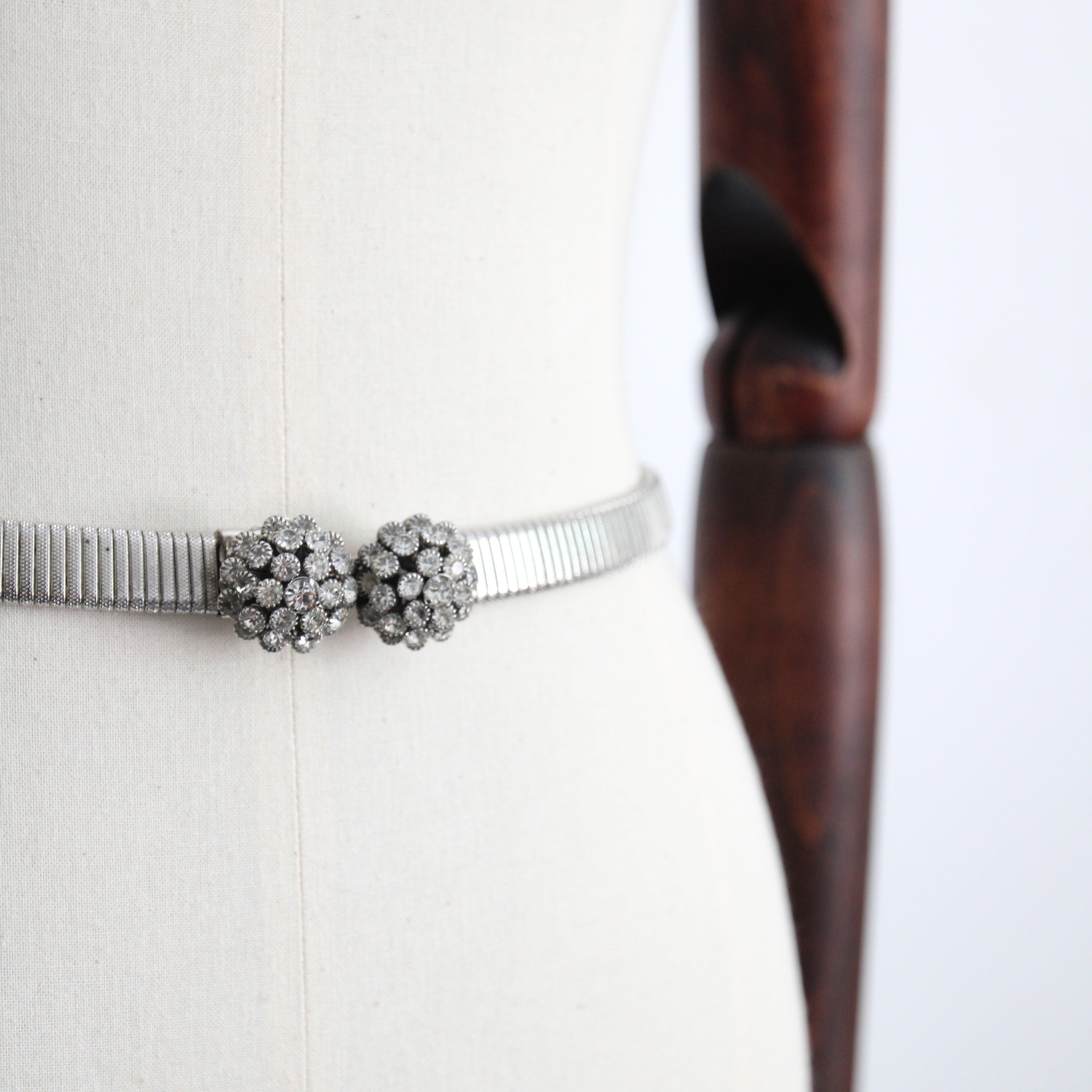 This truly spectacular 1960's statement belt, composed of two claw set rhinestone domes as a central buckle feature, on a silver toned metal base, from which a wide strand of snake chain joins the clasp, is the perfect finishing touch to your