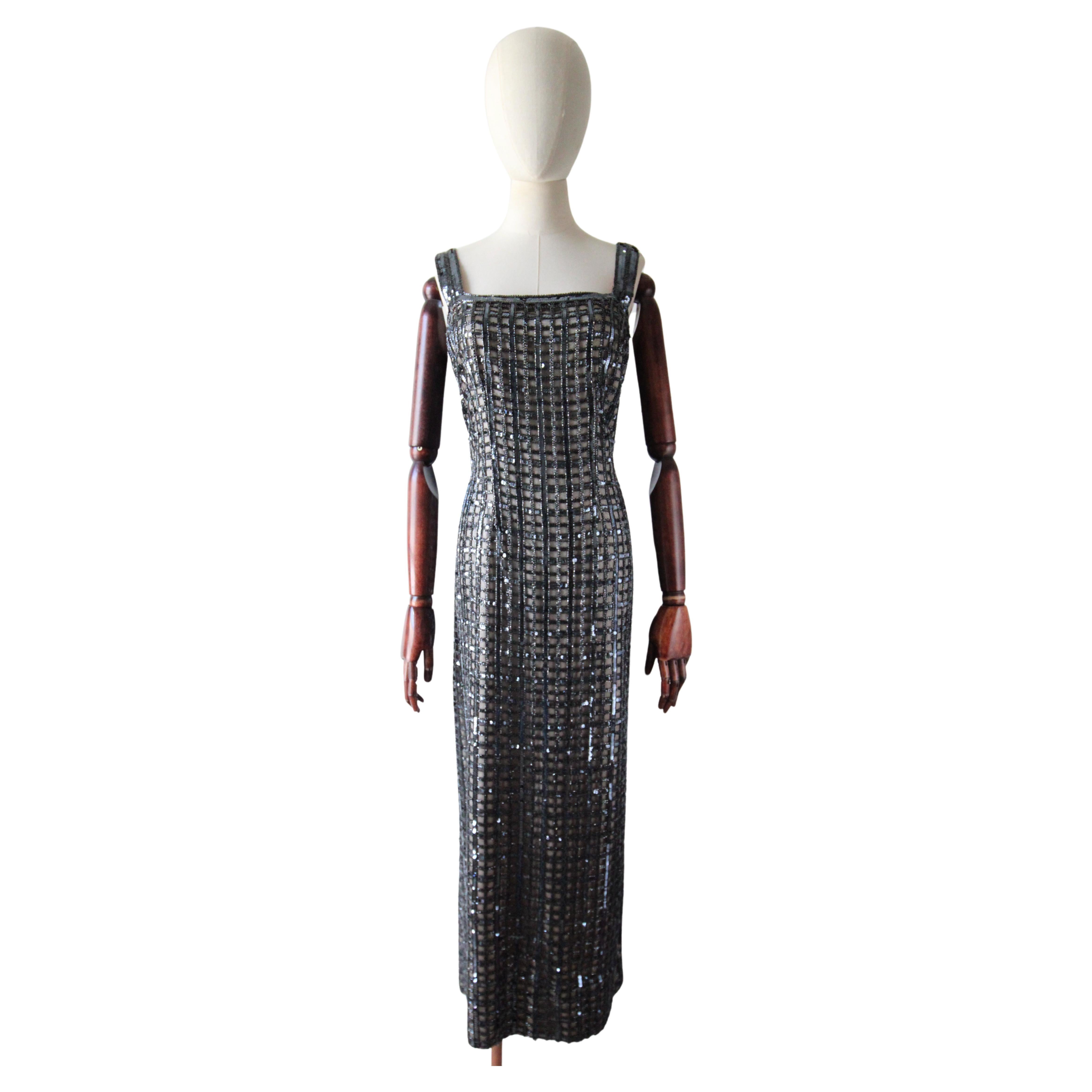 This truly mesmerising 1960's fully sequin and bead embellished dress on a black tulle base which is overlaid upon a champagne coloured satin, is a true masterpiece to behold. The dark silver sequins, are framed by gun metal grey glass bugle beads