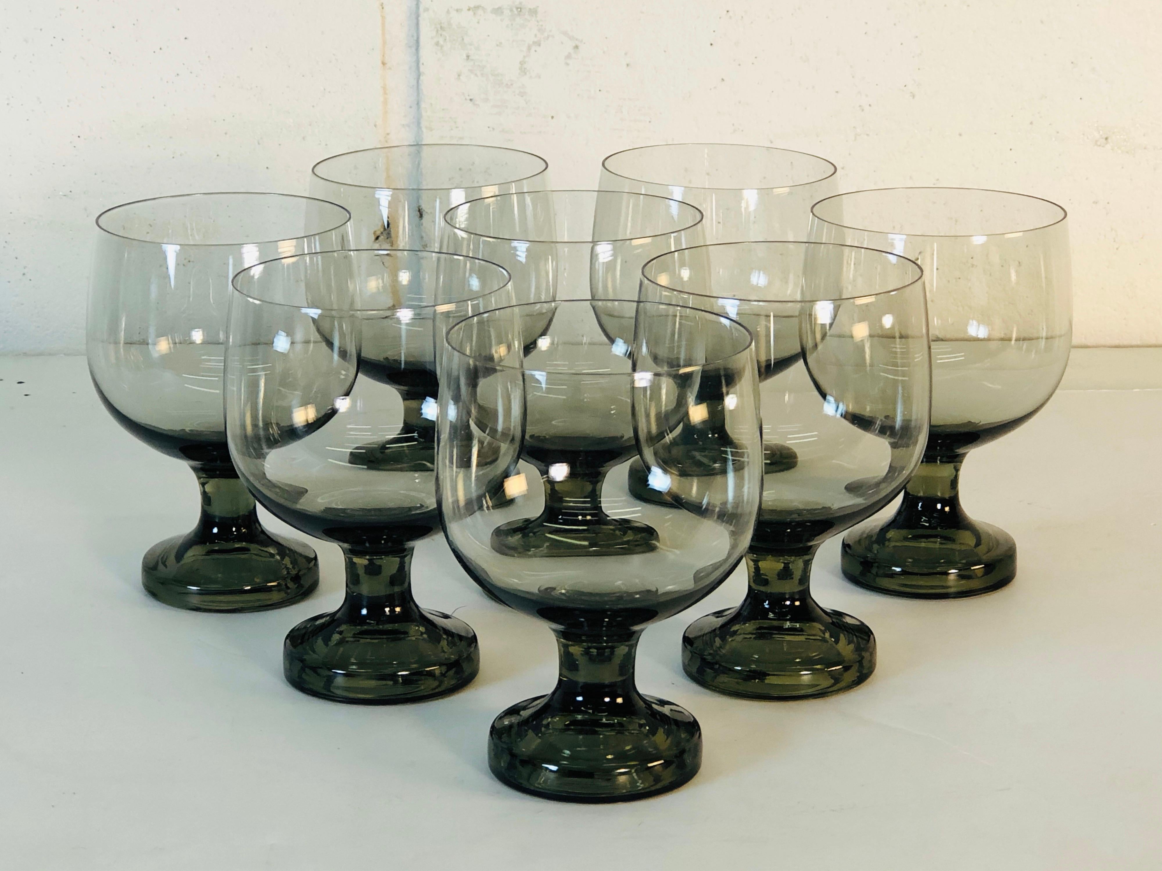 Vintage 1960s set of eight smoked glass goblets attributed to Orrefors glass. Solid base that graduates up to a delicate bowl. No marks.