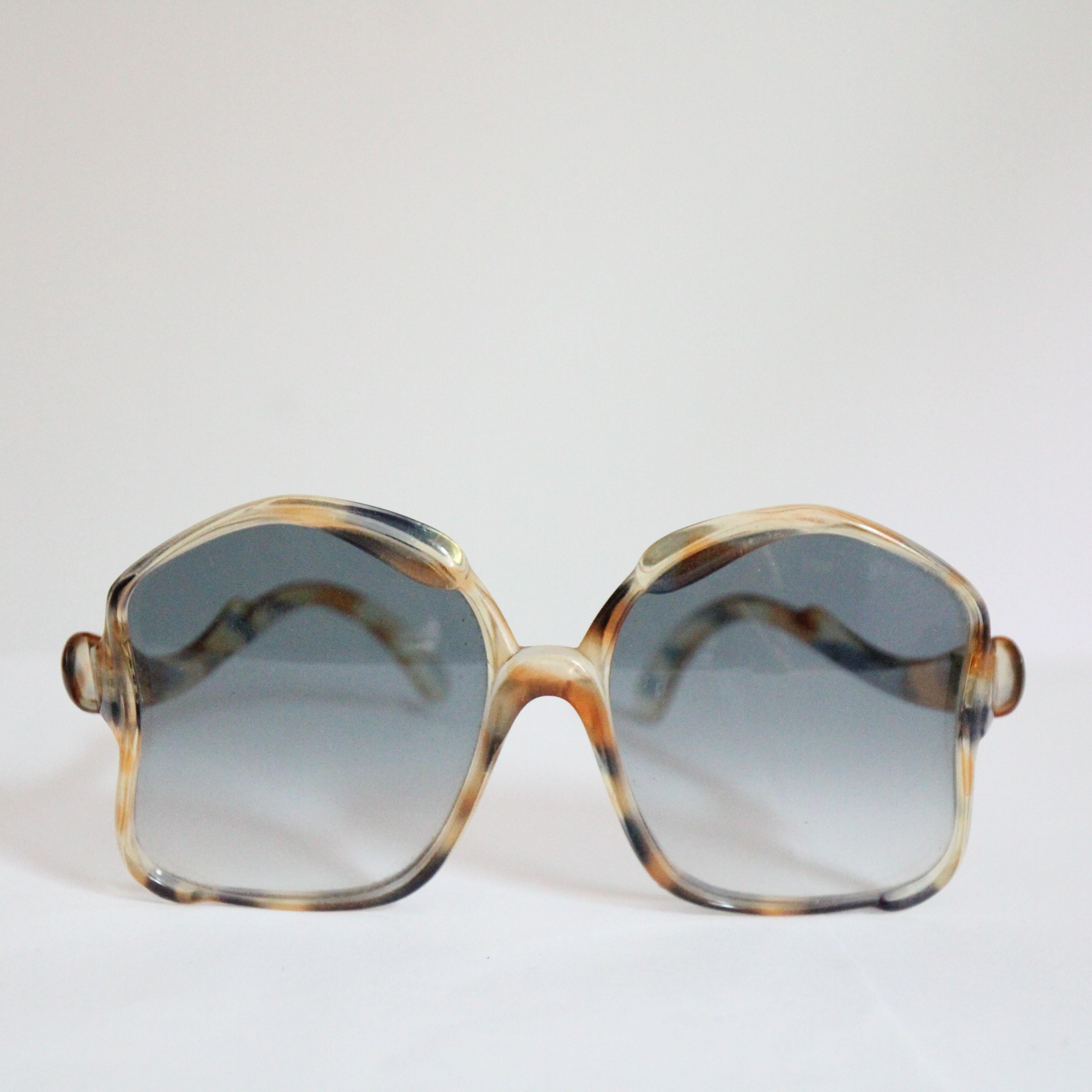 Este icónico par de gafas de sol francesas de los años 60, acentuadas con un estampado de carey en tonos tostados y azules, son el accesorio perfecto para los días soleados.
Los llamativos cristales curvados presentan un sombreado ombre en un sutil