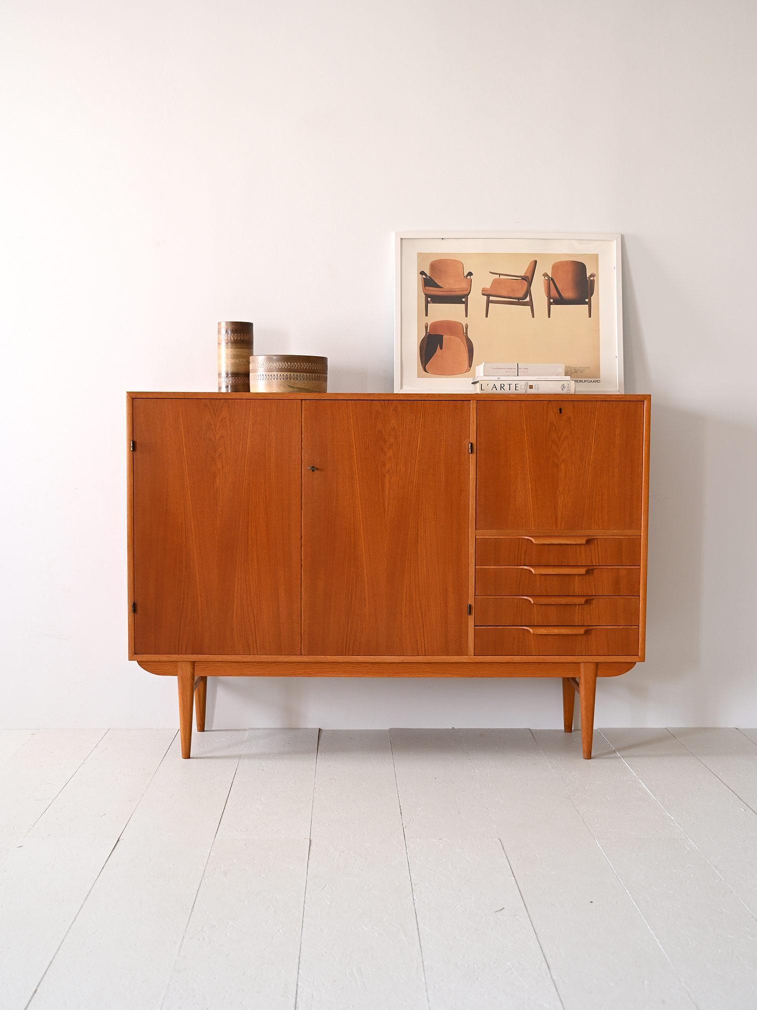 Scandinavian sideboard with doors and drawers.

Original 1960s cabinet consisting of a teak frame and oak legs and profiles. 
It features a storage compartment closed by two lockable hinged doors and on the right side are a flap, also lockable, and