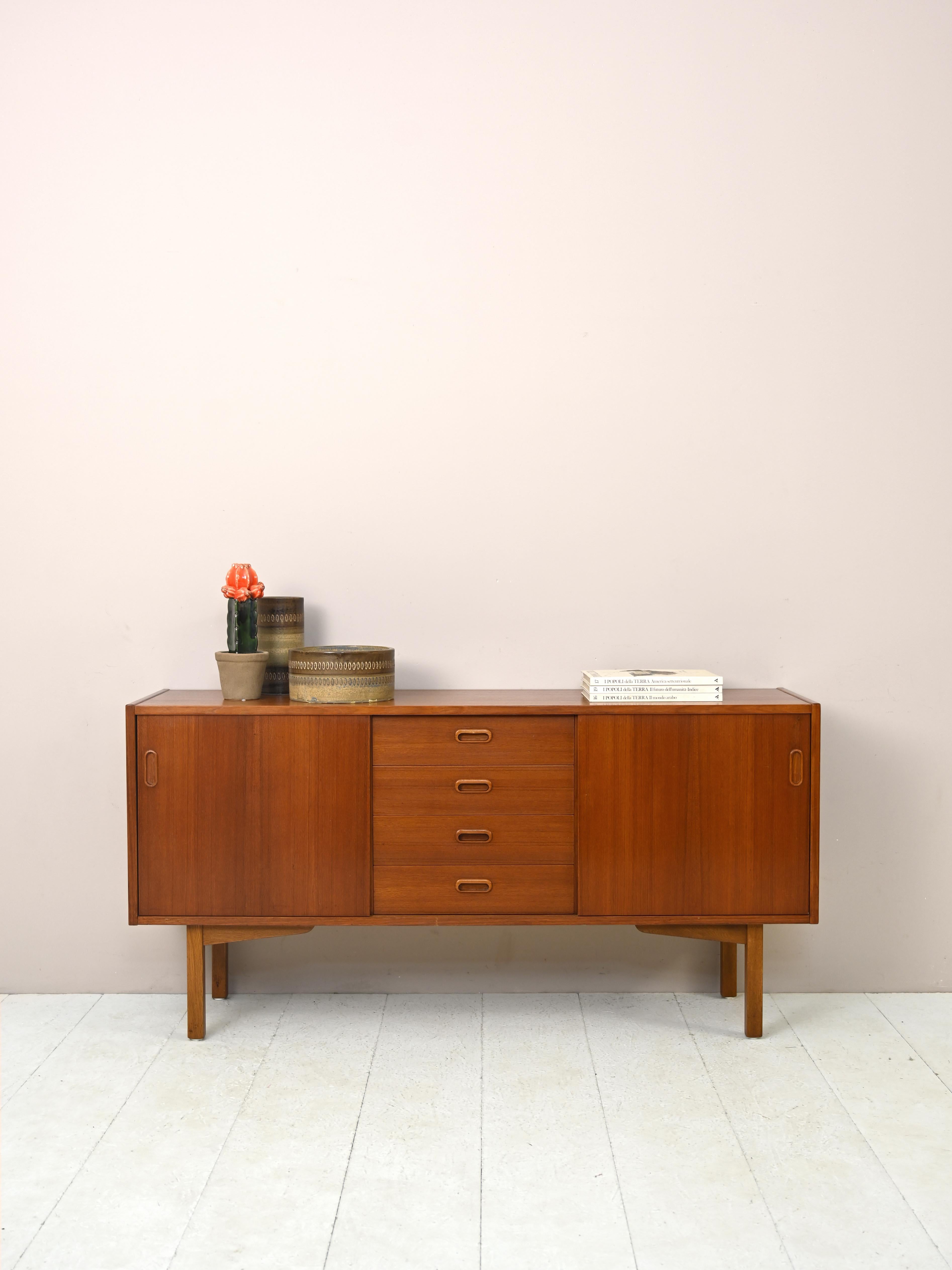 Scandinavian modernist sideboard.

A piece of furniture with a Classic and elegant style, it features 4 central drawers and two sliding doors on the sides.
The carved wooden handle and squared legs give it a modern look, suitable for embellishing