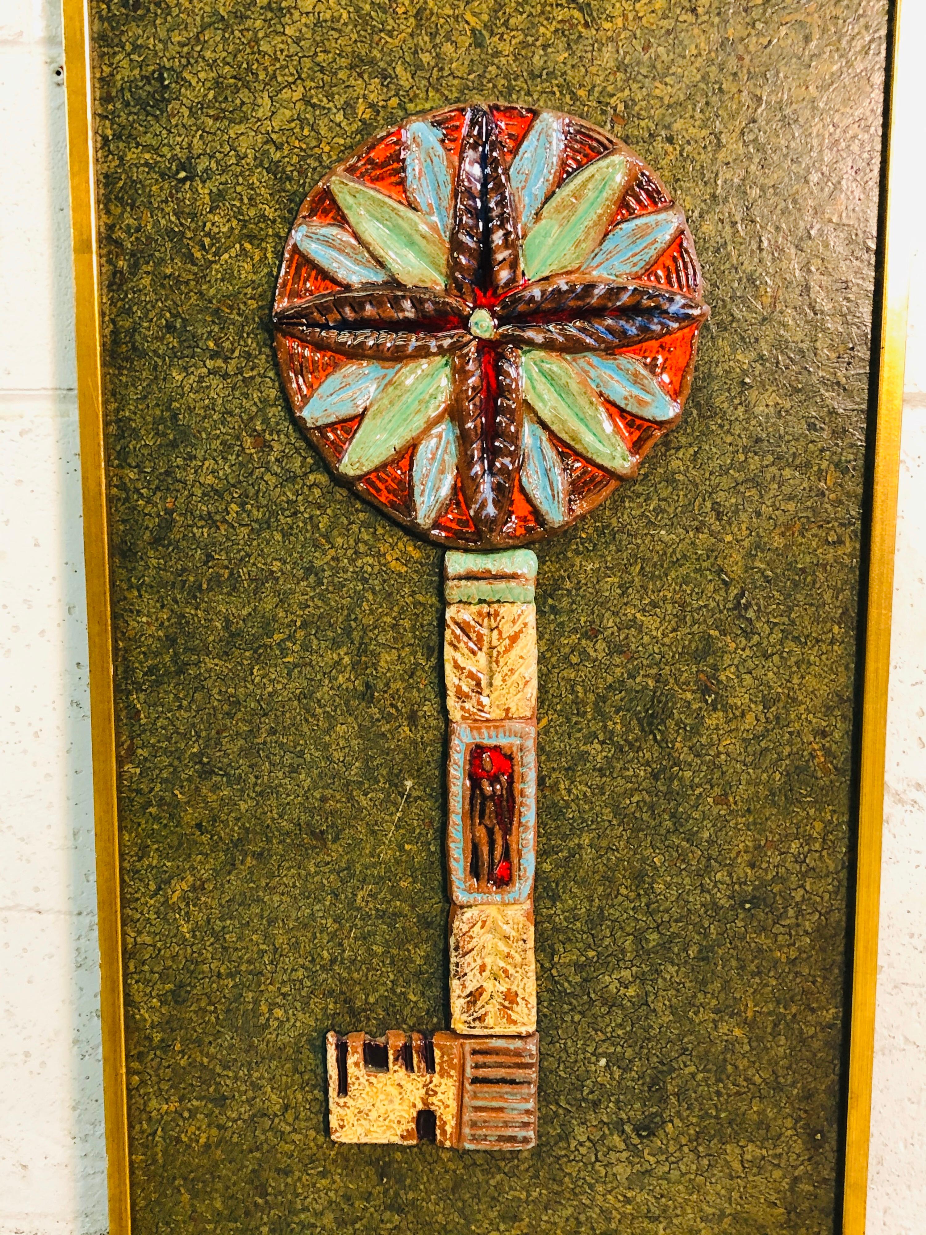 Vintage 1960s abstract tiled key design wall art. The art has multicolored tile pieces that show a large key design. The tile has a nice high gloss and great color. The matte is green and the wood frame is painted gold. Some light wear to the paint.