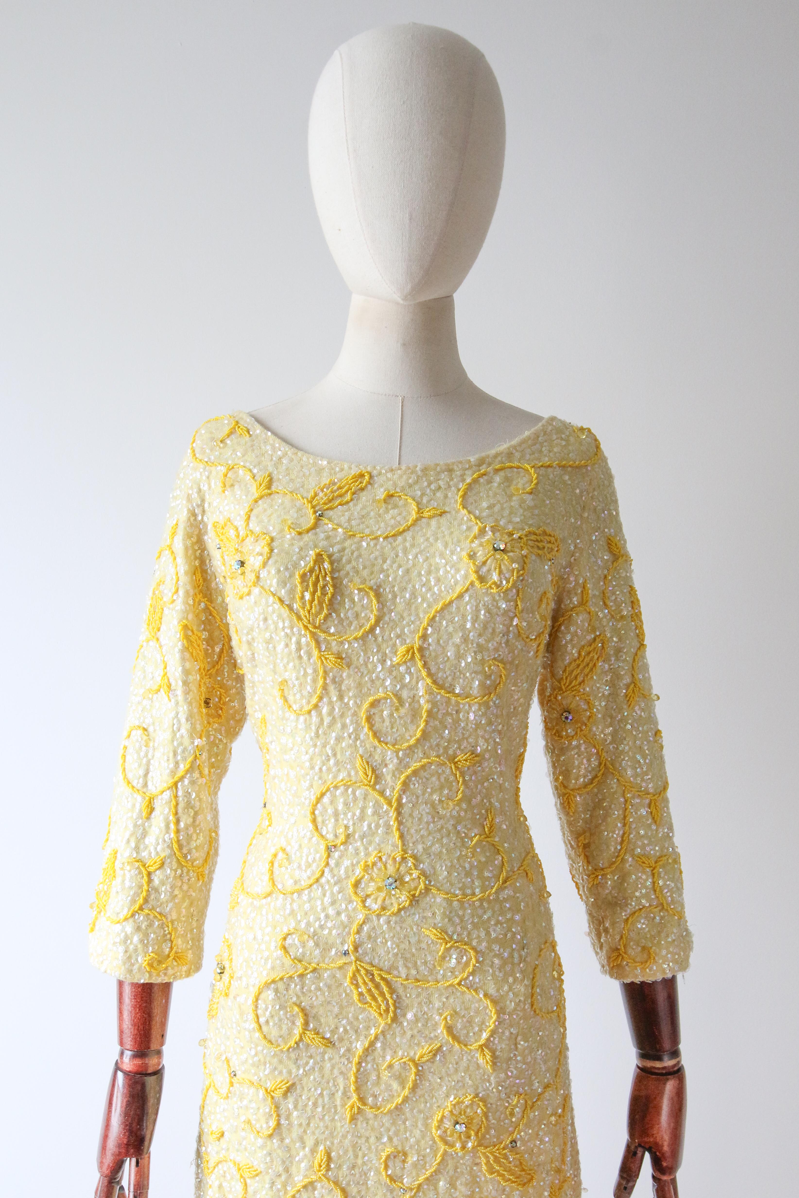 Dieses atemberaubende Kleid aus gelber Strickwolle aus den 1960er Jahren ist komplett mit klaren, schillernden Pailletten verziert und mit floralen Perlendetails aus gelben Rocaille-Perlen und schillernden Strasssteinen in Krallenform versehen.

Der
