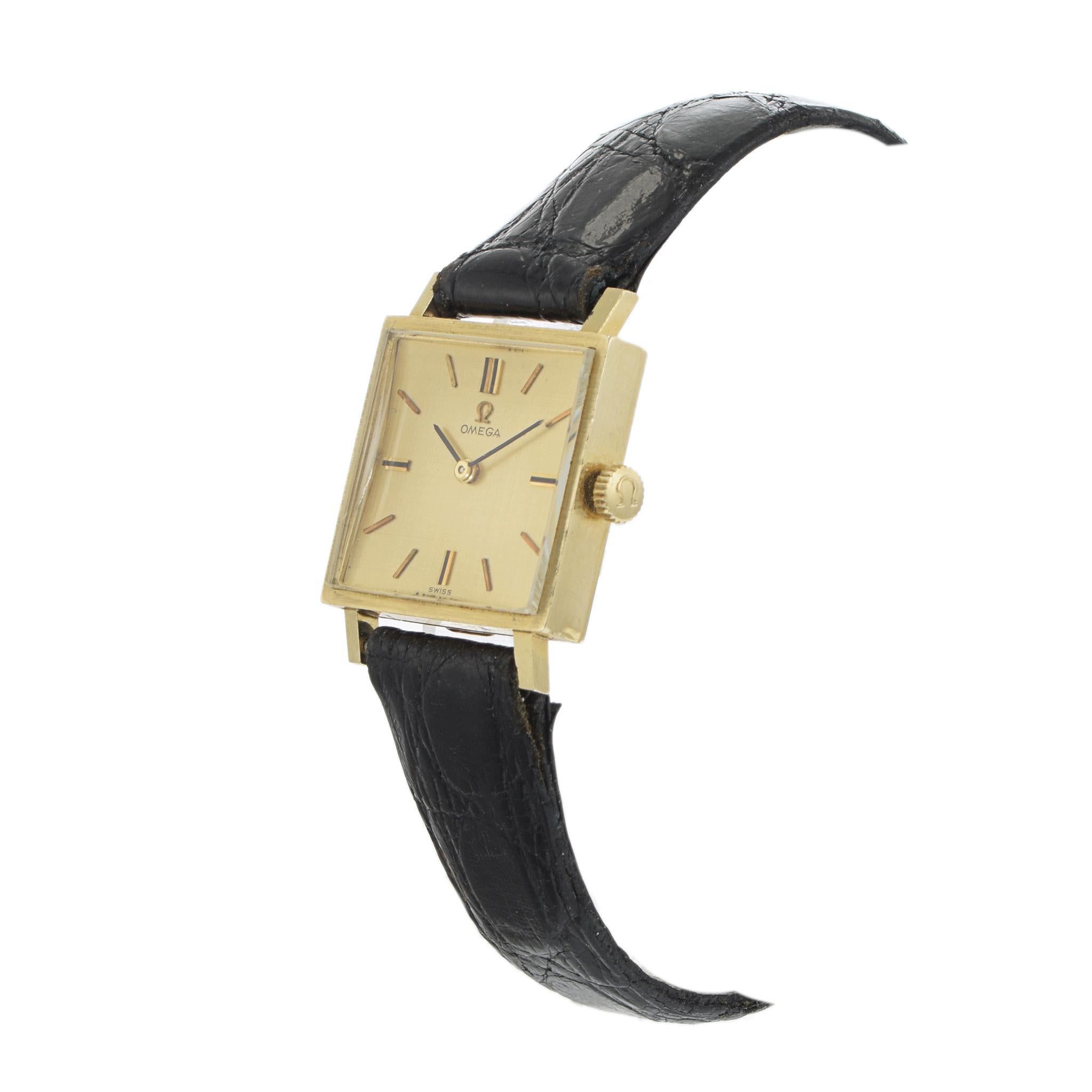 Orologio manuale d'epoca Omega 1963 in oro giallo 14K. Questo elegante orologio è realizzato in oro giallo 14 carati. L'orologio presenta un quadrante quadrato con indici minimalisti e un elegante cinturino Omega in pelle nera con fibbia. L'orologio