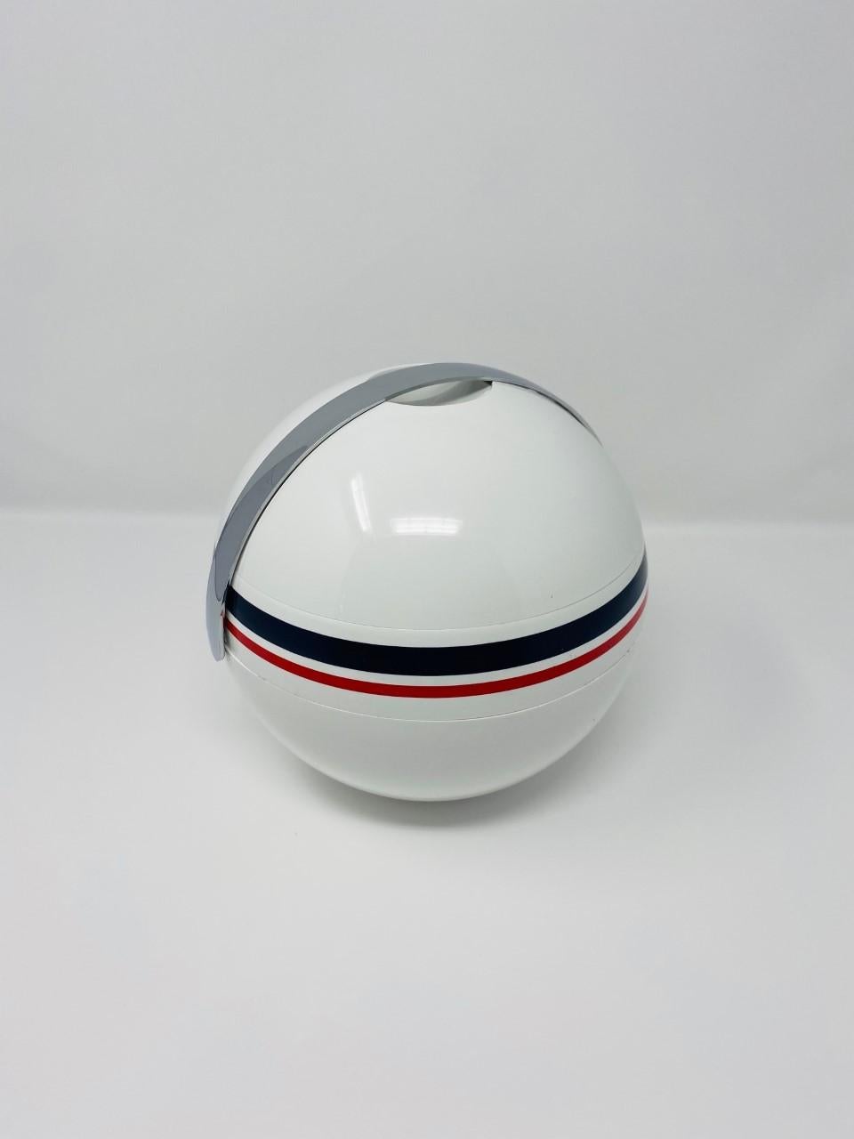 Striking and high design piece created by Paolo Tilche for Guzzini. It’s Space Age design consists of an ecru sphere with navy blue and red stripes with a silver chrome handle that accentuates the special design. The ice bucket is complemented by a