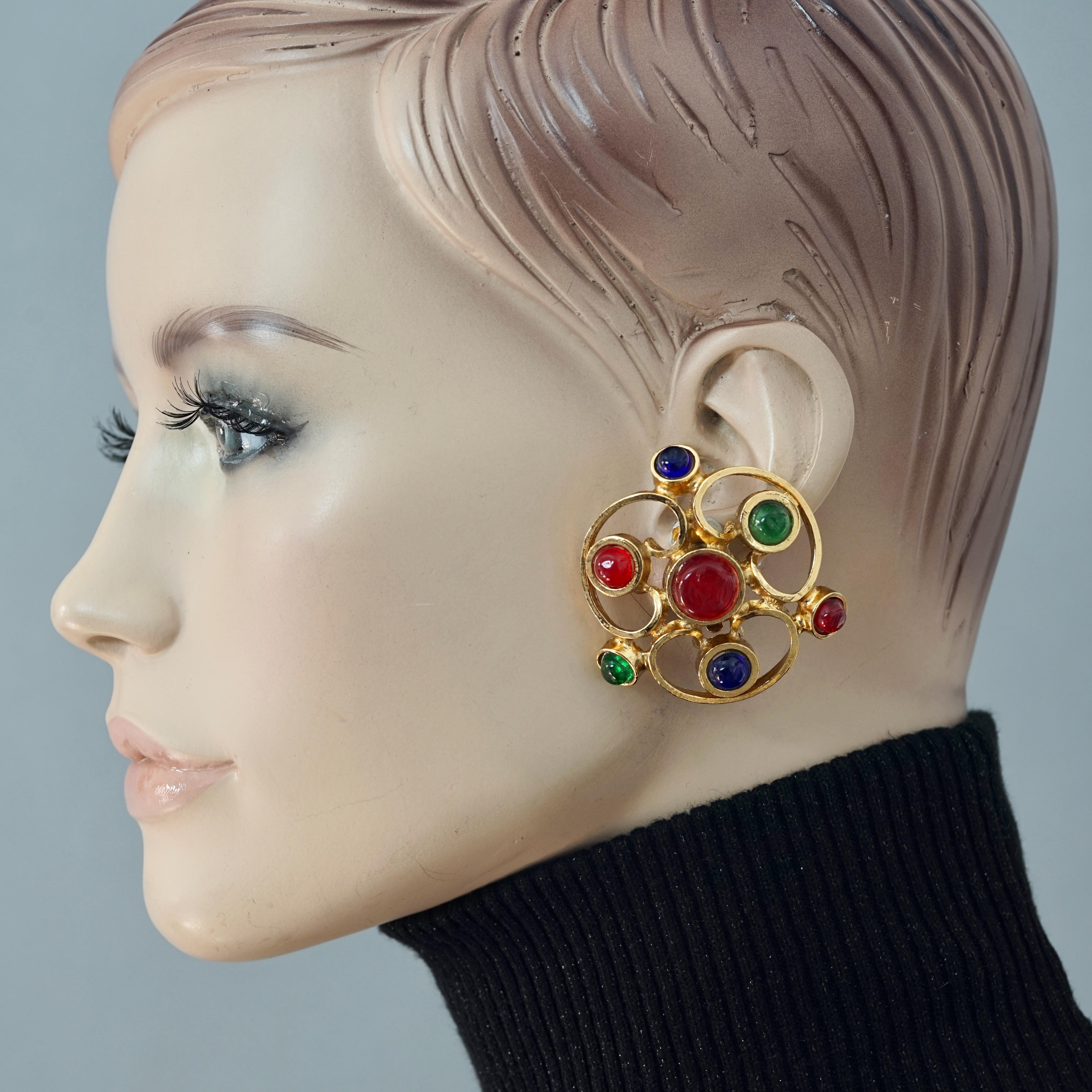 Vintage 1970 Massive CHANEL Gripoix Openwork Earrings

Measurements:
Height: 2 1/8 inches (5.39 cm)
Width: 2 inches (5.08 cm)

Features:
- 100% Authentic CHANEL.
- Massive openwork earrings.
- Embellished with Sapphire, Emerald and Ruby gripoix.
-