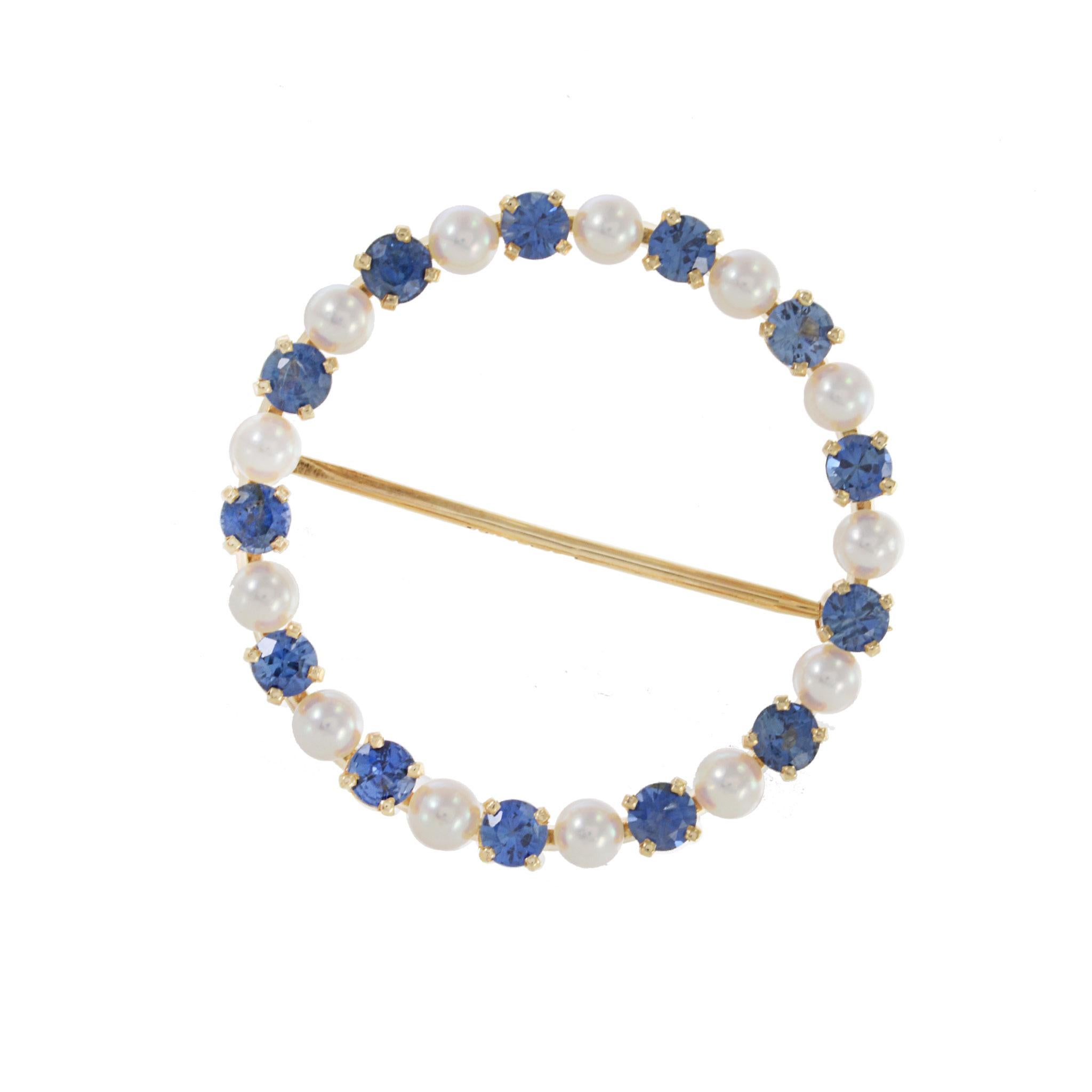 Spilla a cerchio in oro giallo 14KT con perle e zaffiri blu, vintage anni '70. Con un peso di 5,3 grammi, questo incantevole pezzo alterna perle bianche da 3 mm e zaffiri blu, creando un design classico. Aggiungi un tocco di eleganza senza tempo al