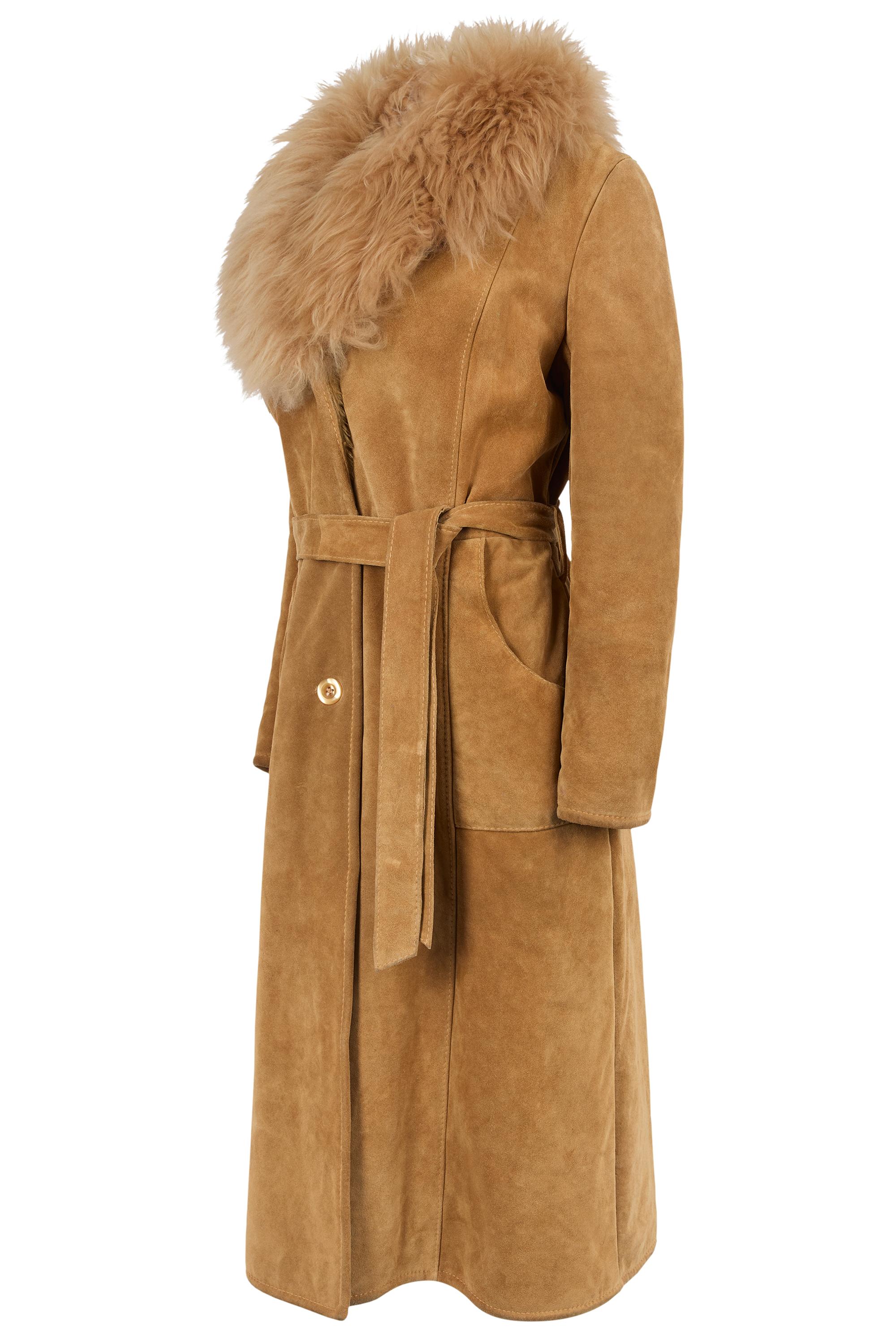 Manteau maxi vintage des années 1970 en daim beige garni de fourrure. Doté d'une fourrure beige sur le col, d'une longueur maxi et d'une ceinture, de deux poches latérales. Se ferme par des boutons sur le devant. 

Vintage, en excellent état.

