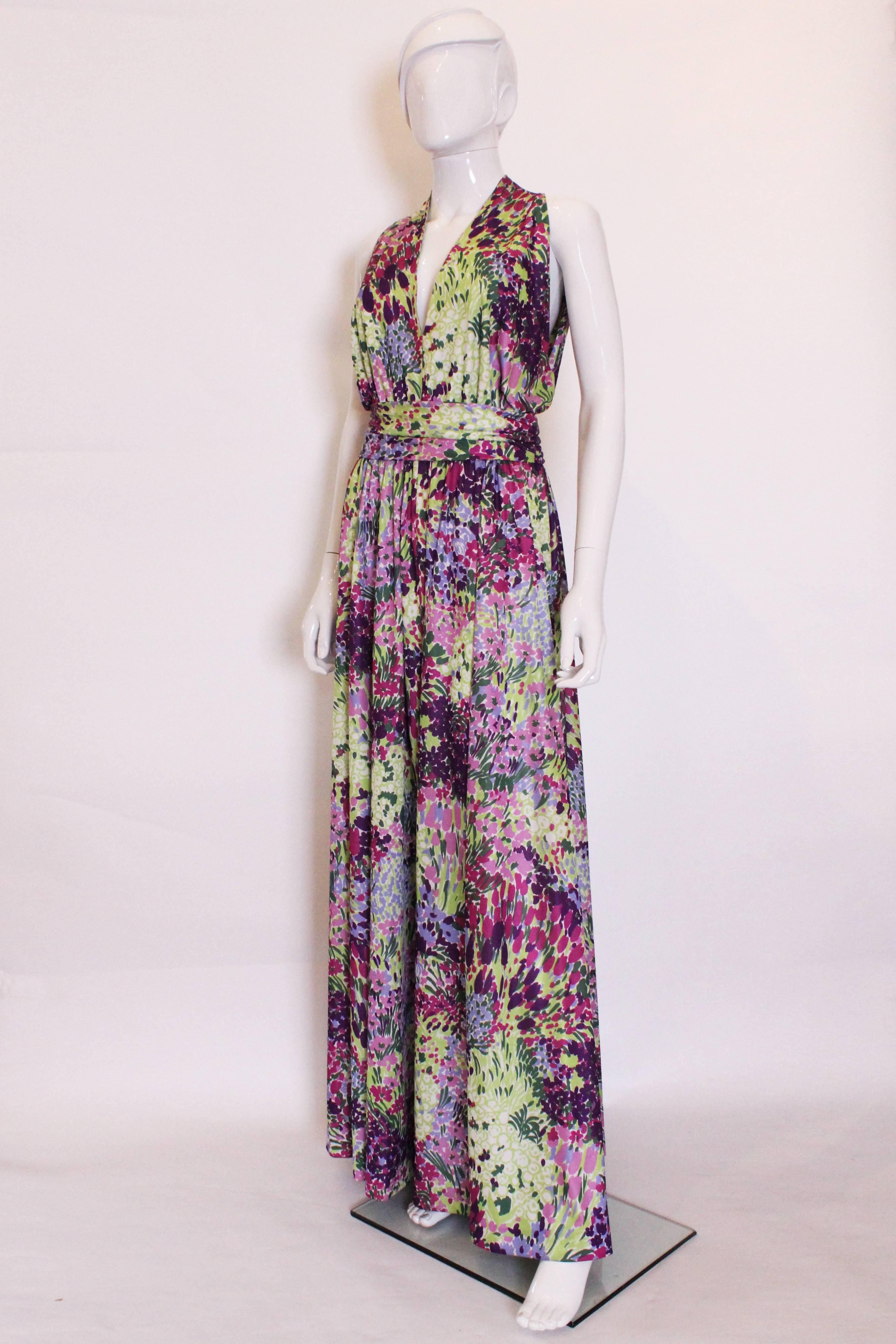 Stunning for Summer. This floral gown by British firm Berketx is a real head turner. In a vivid mix of colours , greens, lilac,  purple and burgundy, it hangs beautifuly. The dress is sleevless with a v neckline,  a button fastening at the neck, and
