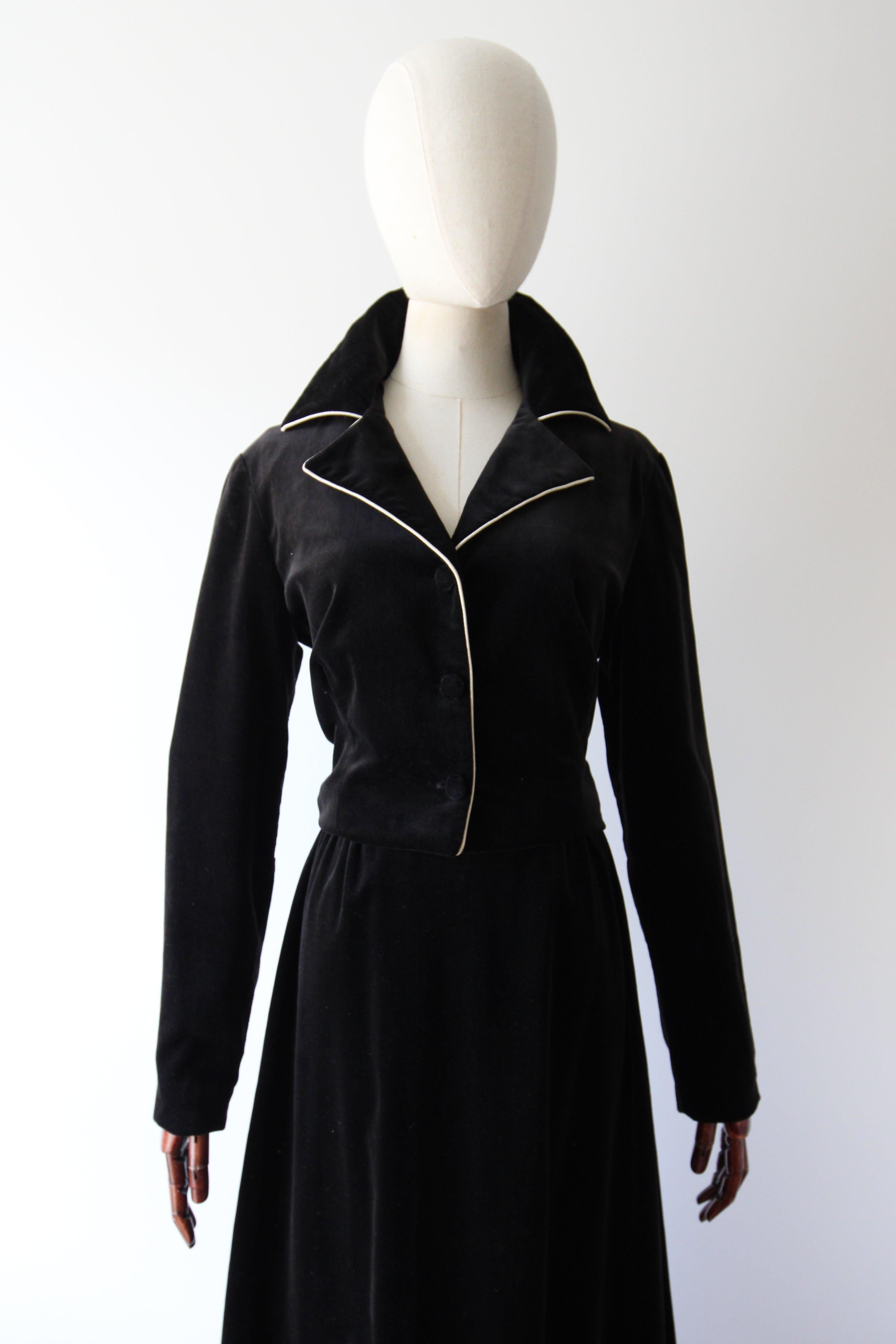 A botanical beauty. This original 1970's set by Catherine Carr, rendered in a black velvet, and accented by rayon appliqués and trims, is the perfect ensemble to add to your vintage collection.

The V shaped neckline of the jacket is framed by a