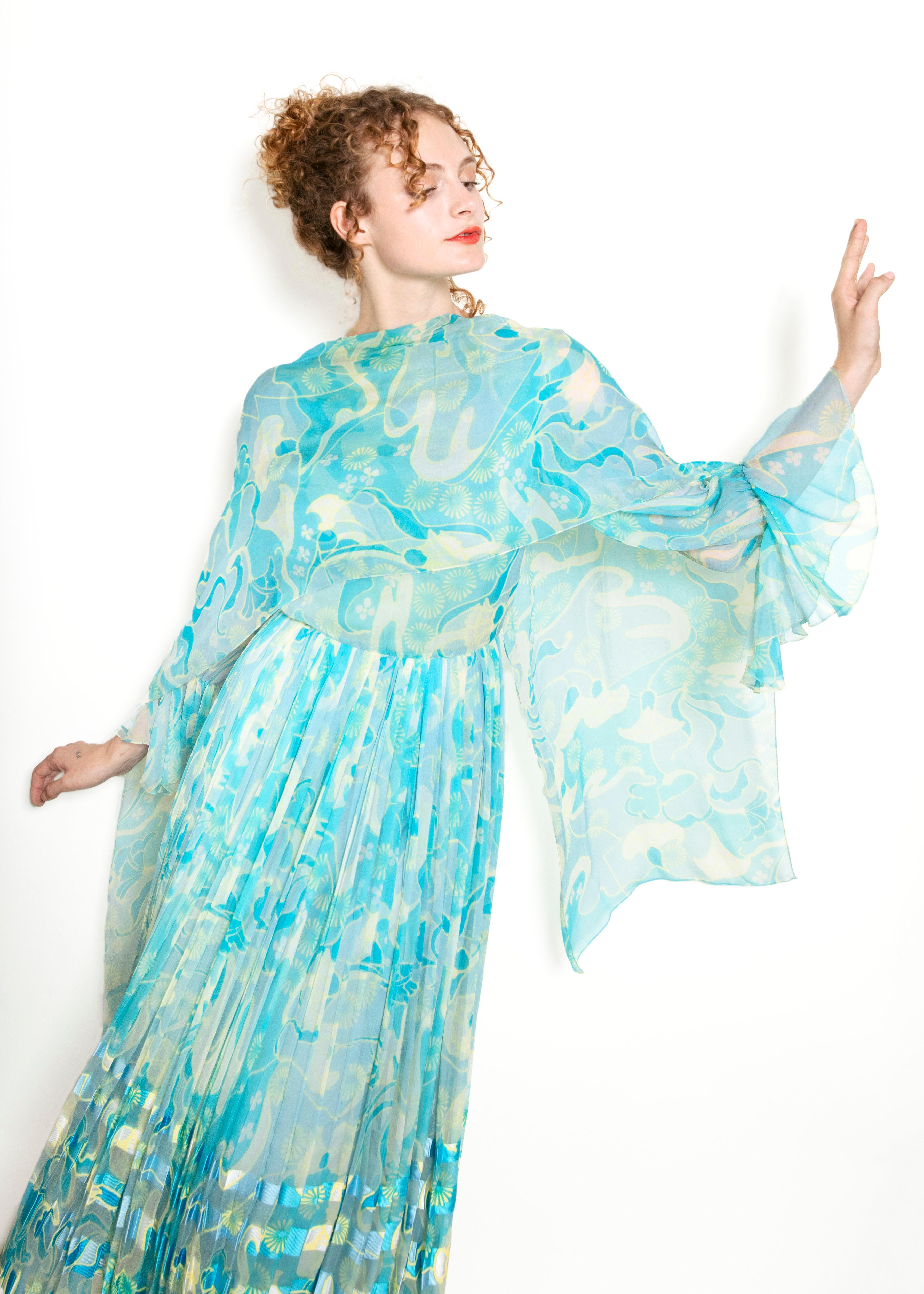 The perfect dress to make a statement – this Vintage 1970's Blue Silk Printed Chiffon Dress is a fashionista's dream come true. Boasting a classic 70's look with its pleated draping and multi-colored silk print, you'll be feeling like a total retro