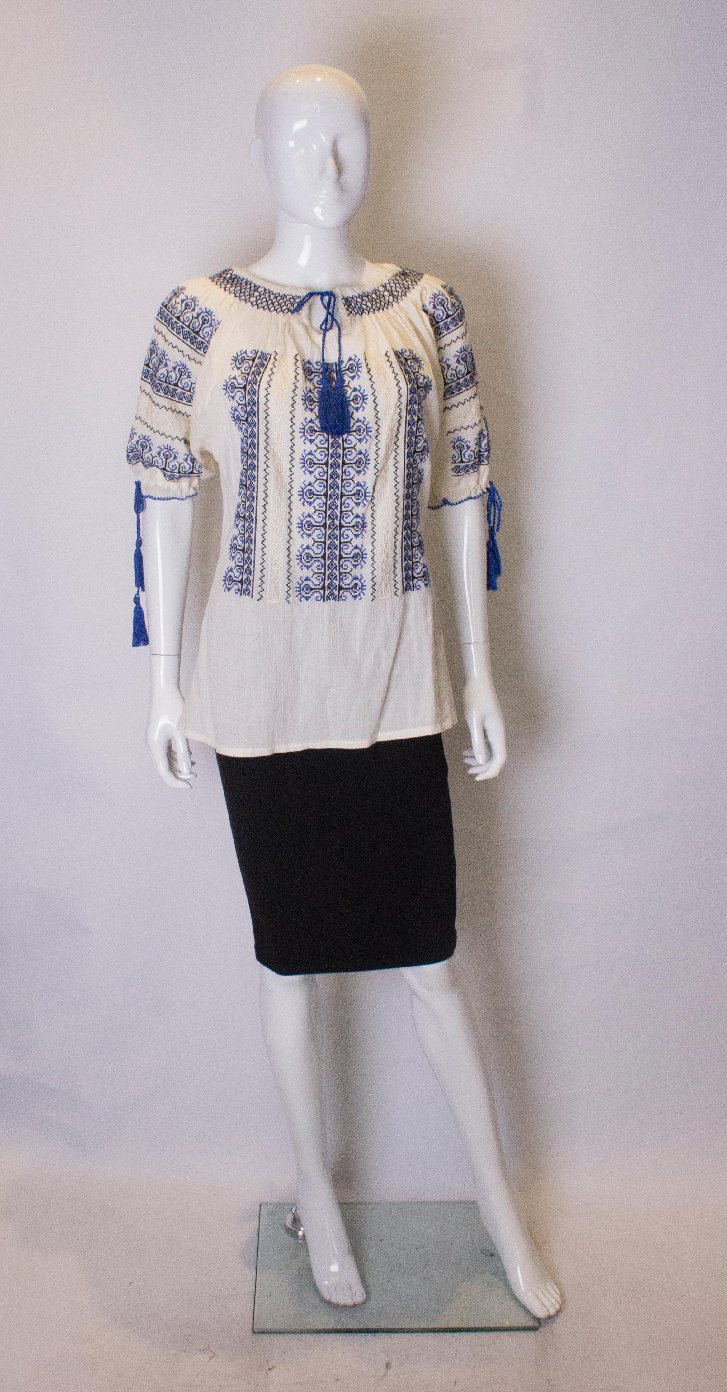 A fun and easy to wear top for Spring /Summer. In an ivory cheesecloth  with blue and black embroidery, the top has a tie neckline and sleeves.