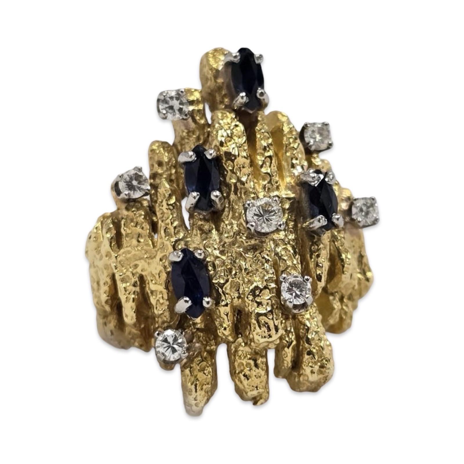 This striking vintage Brutalist ring from the 1970s is crafted in rich 18K yellow gold and showcases a bold, architectural texture characteristic of the era’s avant-garde jewelry design. Set with approximately 1.00 carat of deep blue marquise