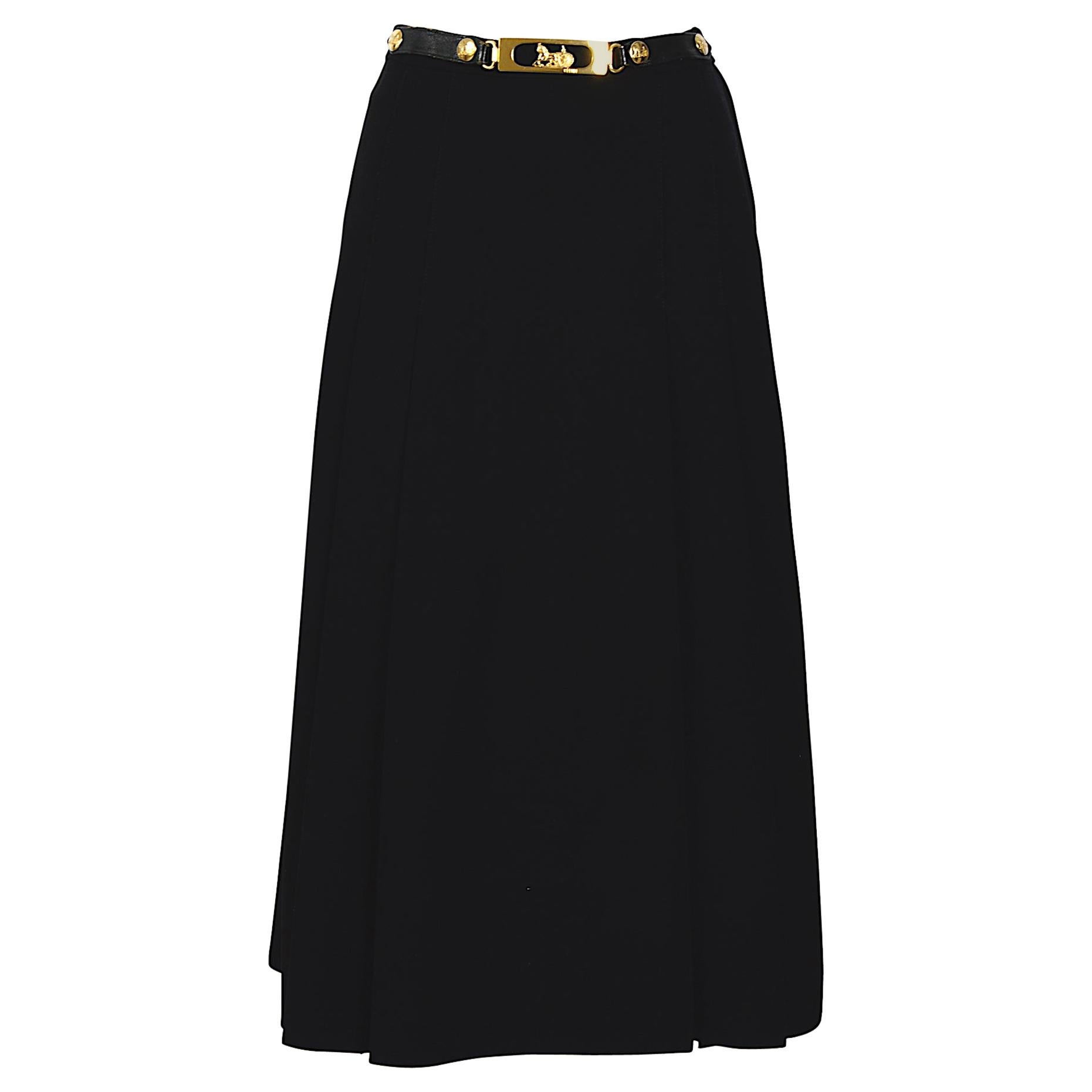 This black gabardine high waisted A-line pleated Céline skirt is the most wanted vintage skirt at this time.
Black patent leather belt-like appliquè at waistband with the signed gold-tone carriage logo and buttons attached.
There is no size label,