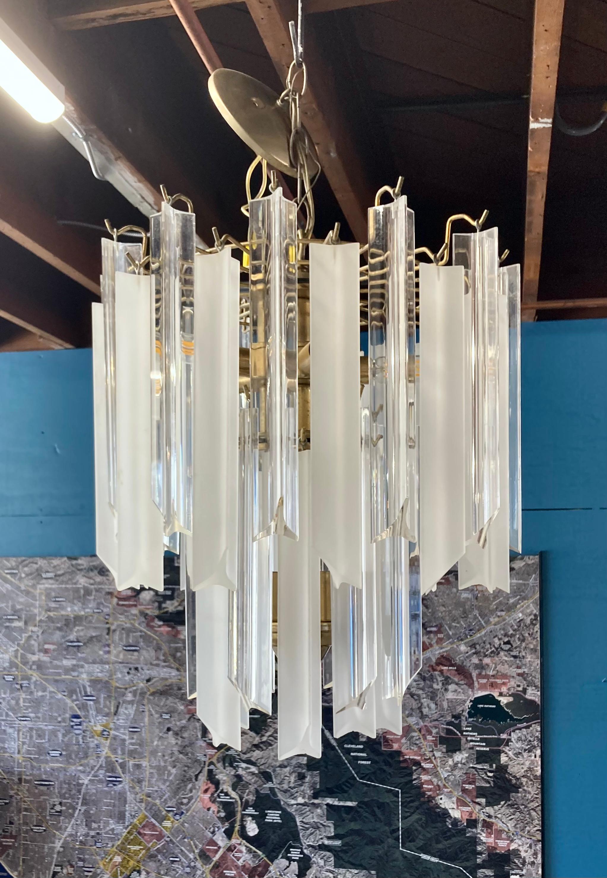 Statement vintage hanging chandelier, made of brass and lucite. Two tiers of alternating clear and frosted lucite prisms. Excellent mid-century piece in great vintage condition. Holds 8 lightbulbs. 

16