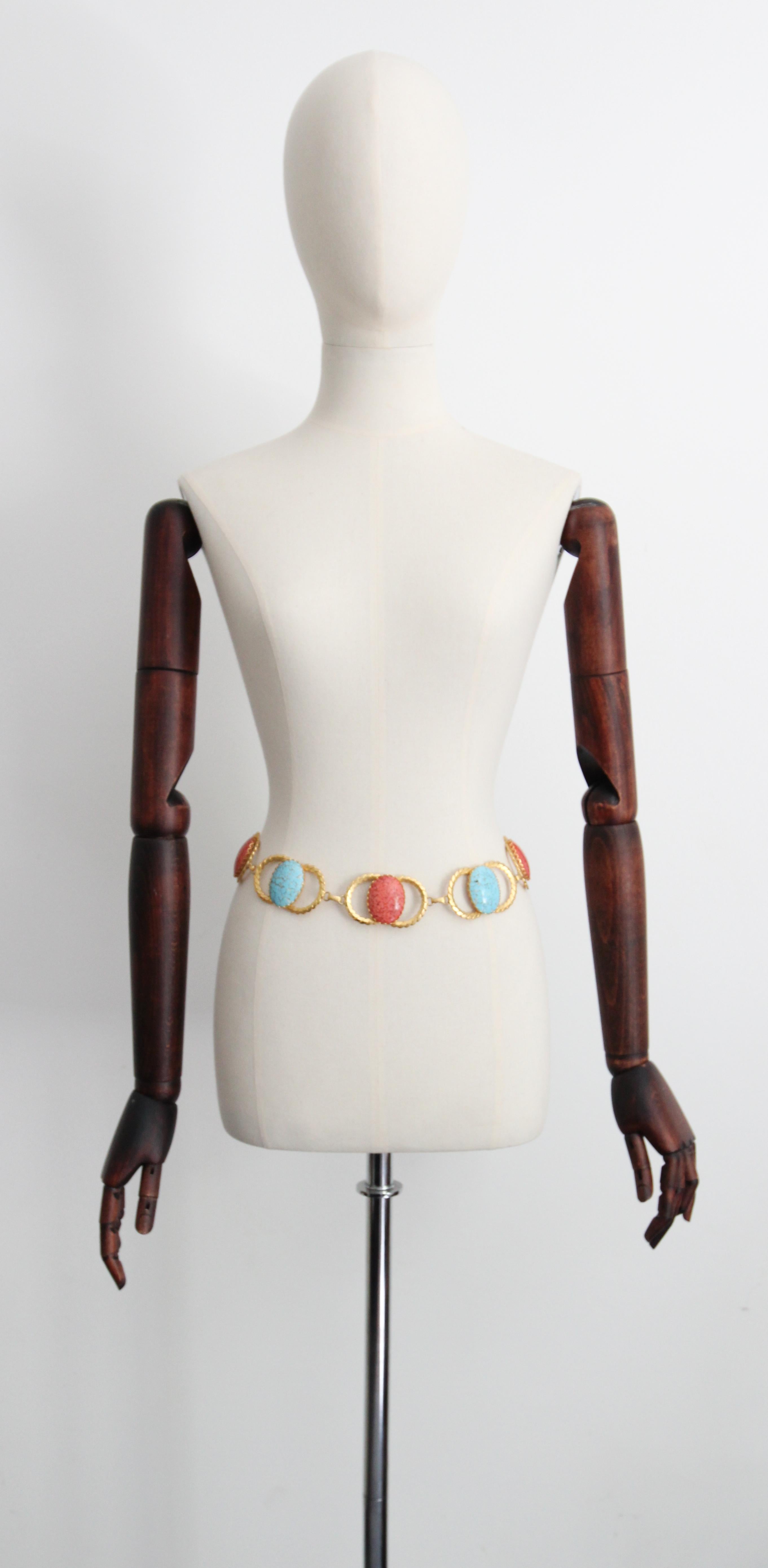 This iconic 1970's belt, made up of interlocking gold metal circles, embellished with central glass cabochons in alternating shades of marbled coral and marbled turquoise, set in petal shaped claw casings, and linked together with engraved loops,