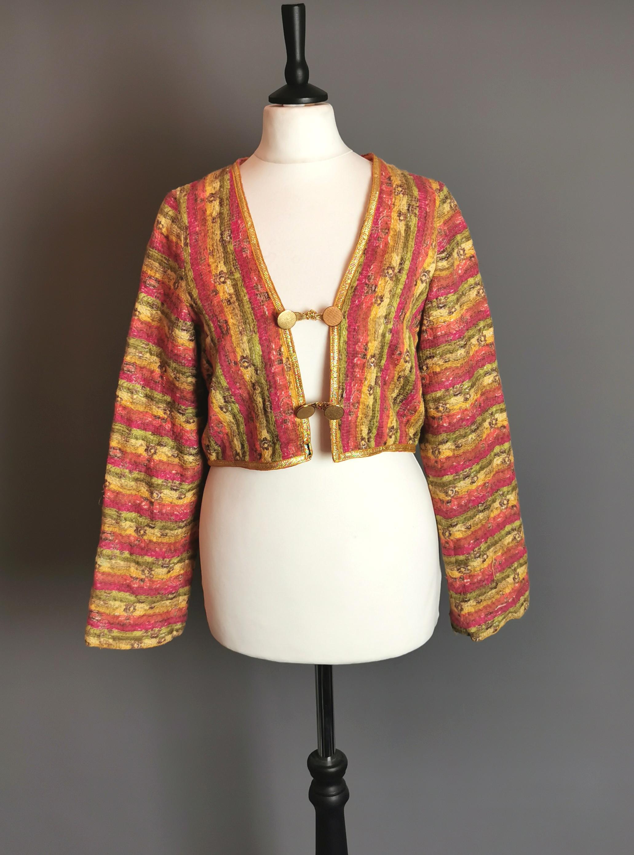 A unique vintage c1970s vibrant cropped jacket.

This is a truly wonderful piece with a bright colourful woven cotton and wool body with a floral print and gold tone metallic thread highlights.

It has gold tone buttons and a gold coloured sateen