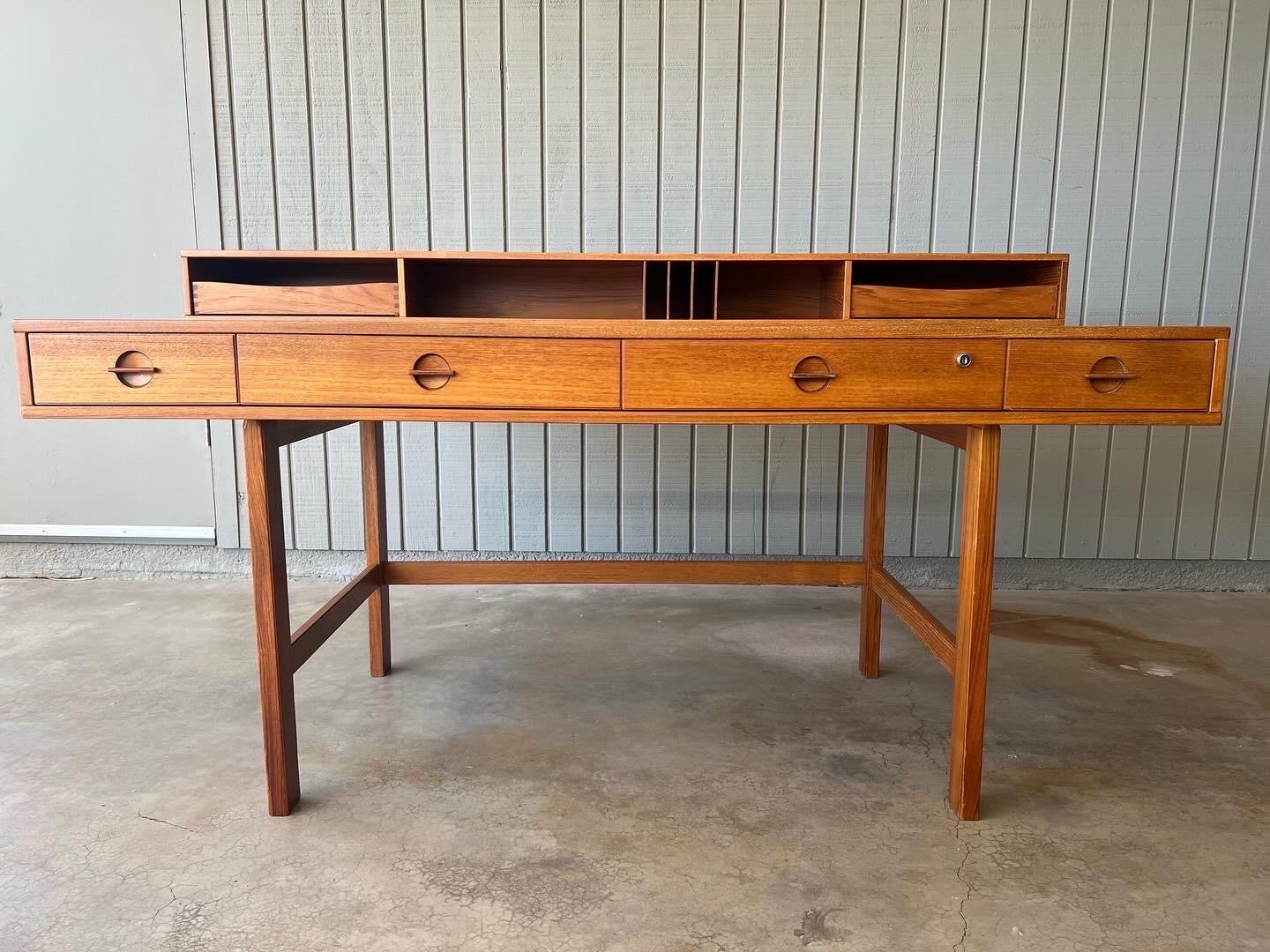 The iconic Løvig teak flip top desk designed by Peter Løvig Nielsen, 1960s, Denmark. It’s versatile in that the back shelf can flip down on its brass hinges to create a larger work surface. The bigger size of this desk is great for modern day work