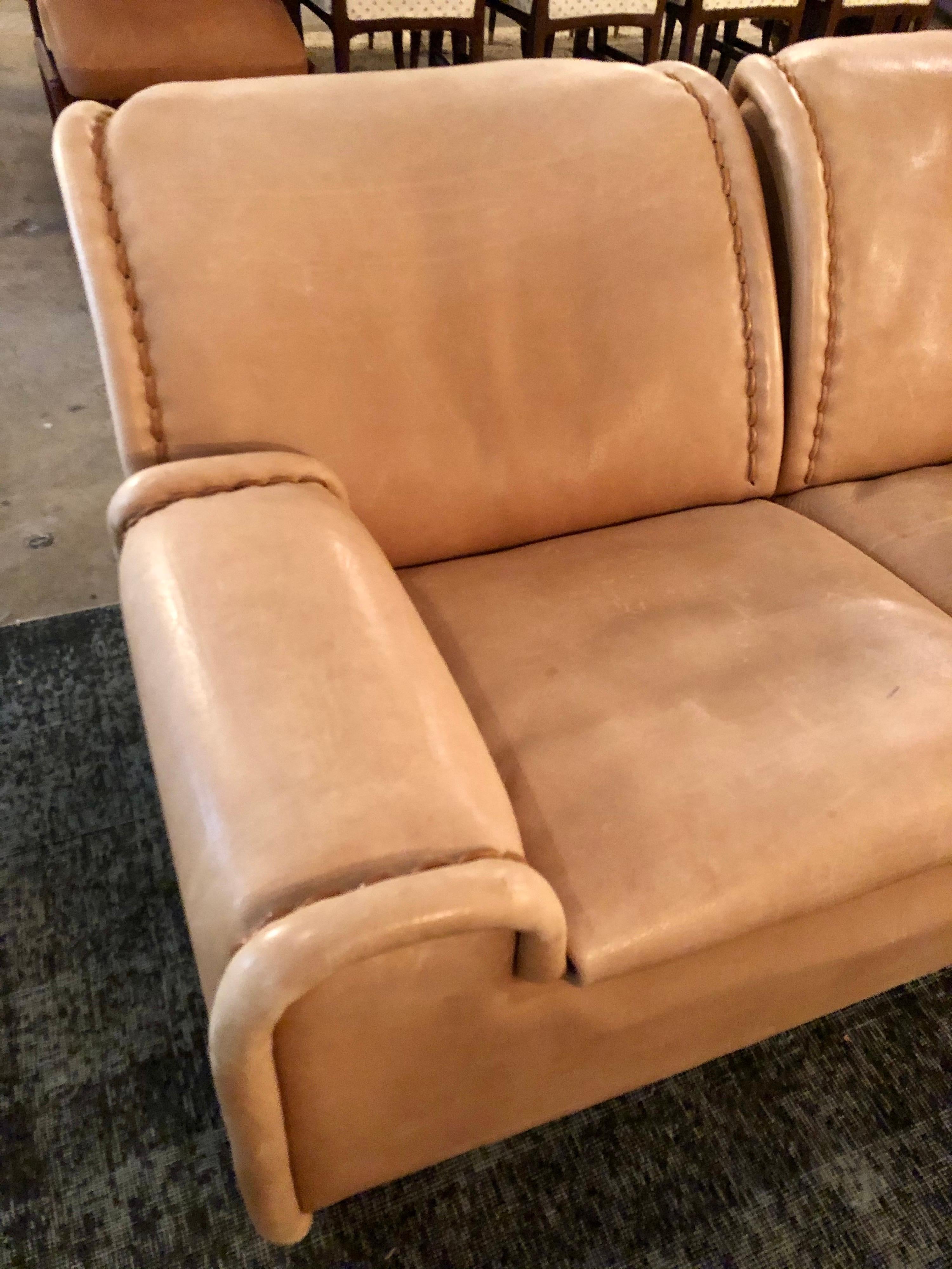 Designed by De Sede, this 'sitting bull' leather sofa is in overall good condition. Nude color leather. The leather is distressed and shows scuffs, scratches, and discoloration, please refer to photos for condition. Gorgeous stitching details. Soft,