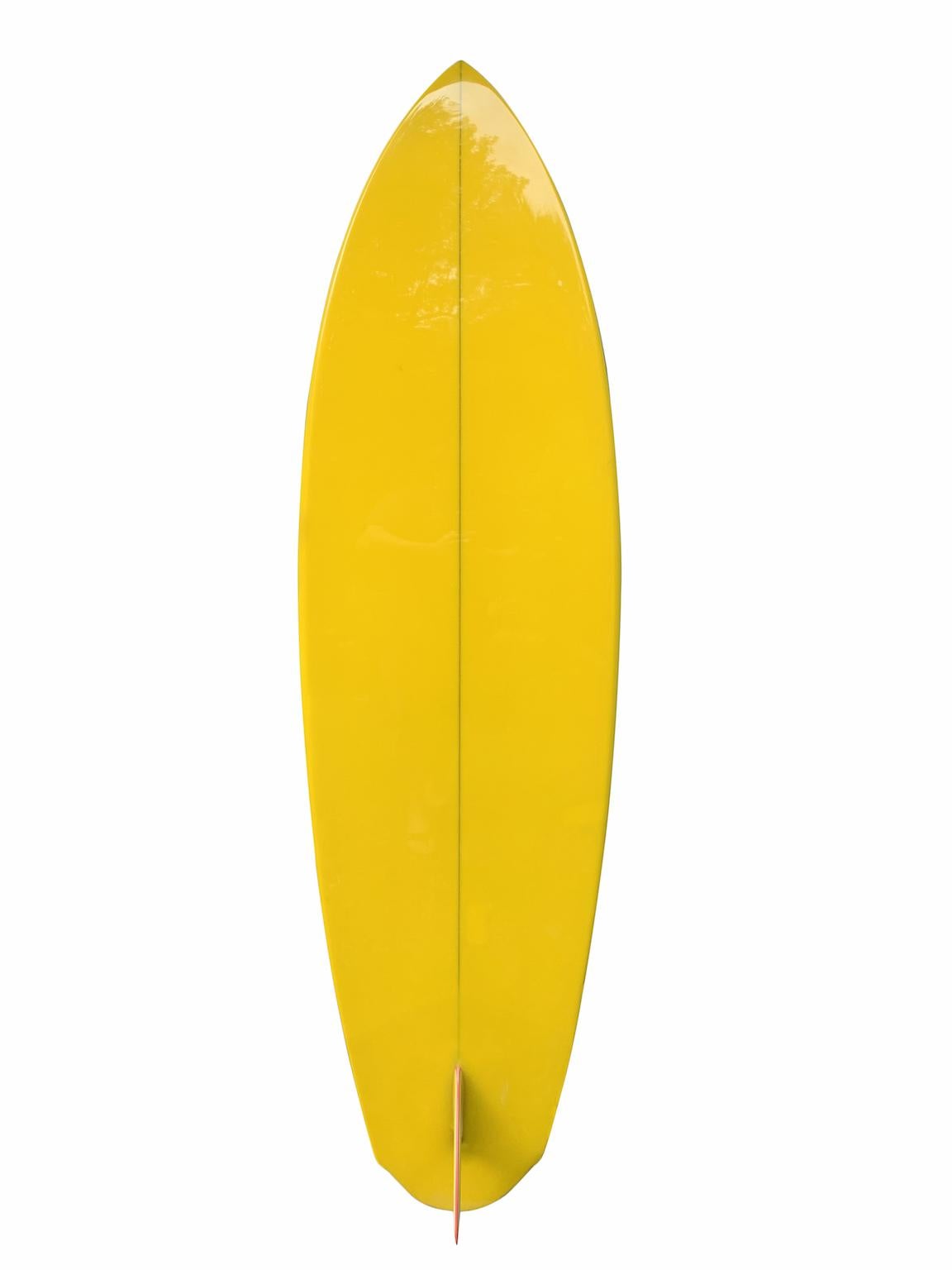 Early 1970s Dick Brewer shaped single fin surfboard. Features a beautiful yellow tint with tri-color glassed on single fin and black pinstriping. Restored to it's original condition by a surfboard restoration expert with over 40 years of experience.
