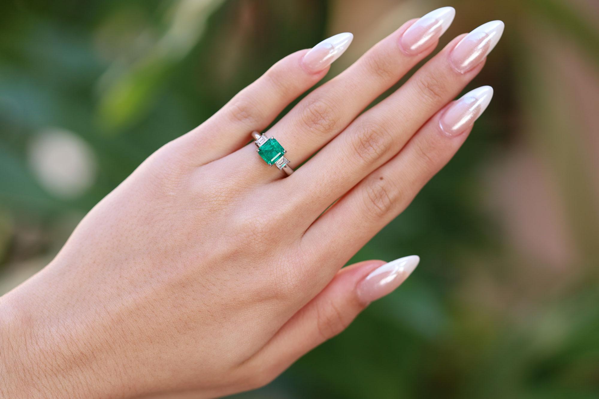 A classic gemstone engagement ring, this 1970s vintage treasure centers upon a rich, deeply saturated green Colombian emerald. GIA certified as natural with verified origin, the square, step cut gem weighs 1.69 carat and is flanked by a pair of
