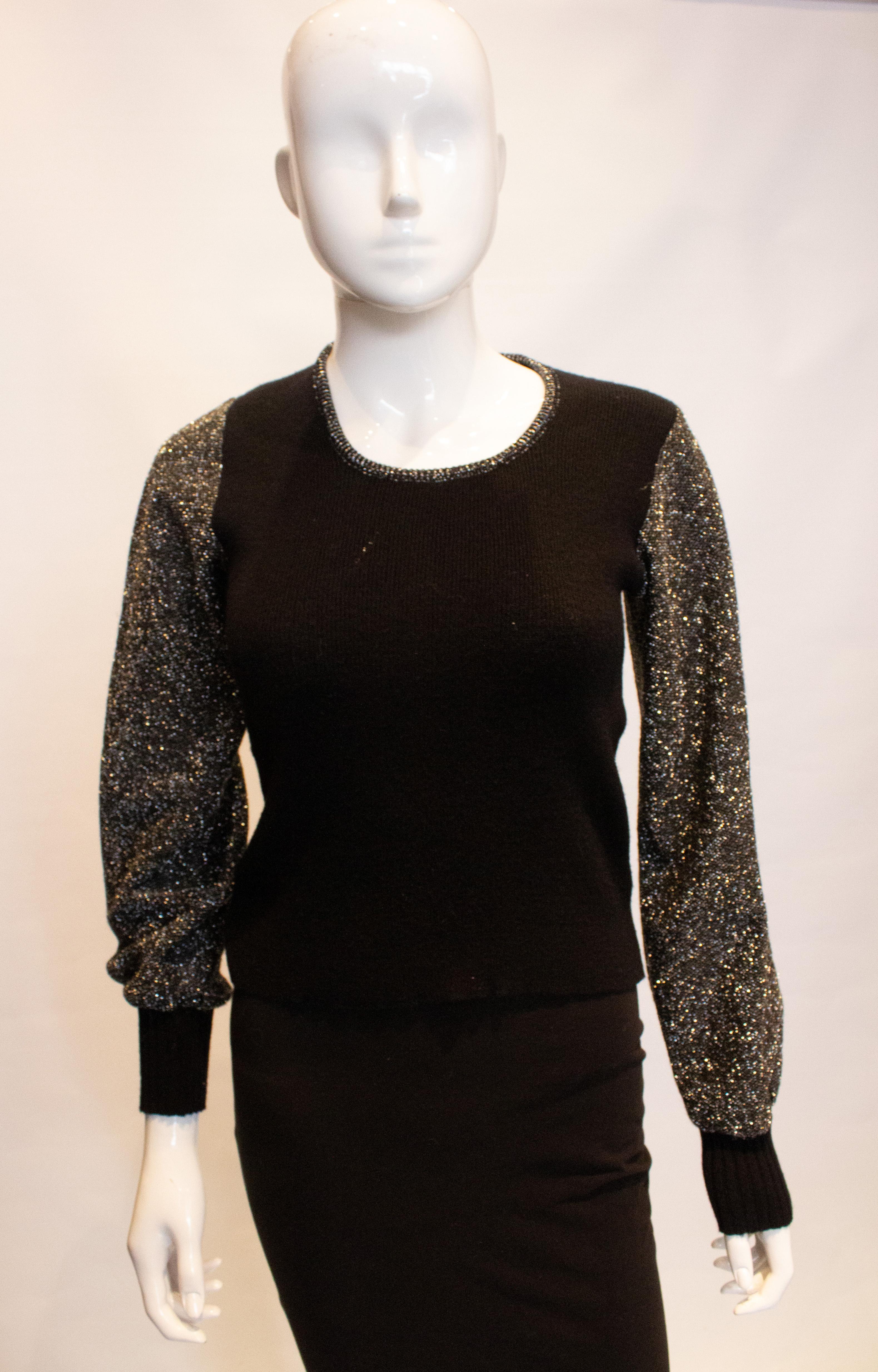 Ein lustiger und leicht zu tragender Vintage-Pullover aus den 1970er Jahren.  Der Pullover hat einen schwarzen Körper,  silberne Ärmel, runder Halsausschnitt und Rippendetails. Maße, Büste 34'' - 37'', Länge 19''